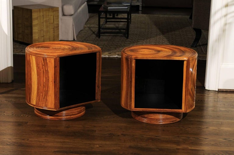 A Killer pair of restored vintage end tables or nightstands, circa 1975. Exceptionally crafted mahogany case construction veneered in spiral bamboo; open display compartment finished in black lacquer. The cabinet is mounted on a swivel base