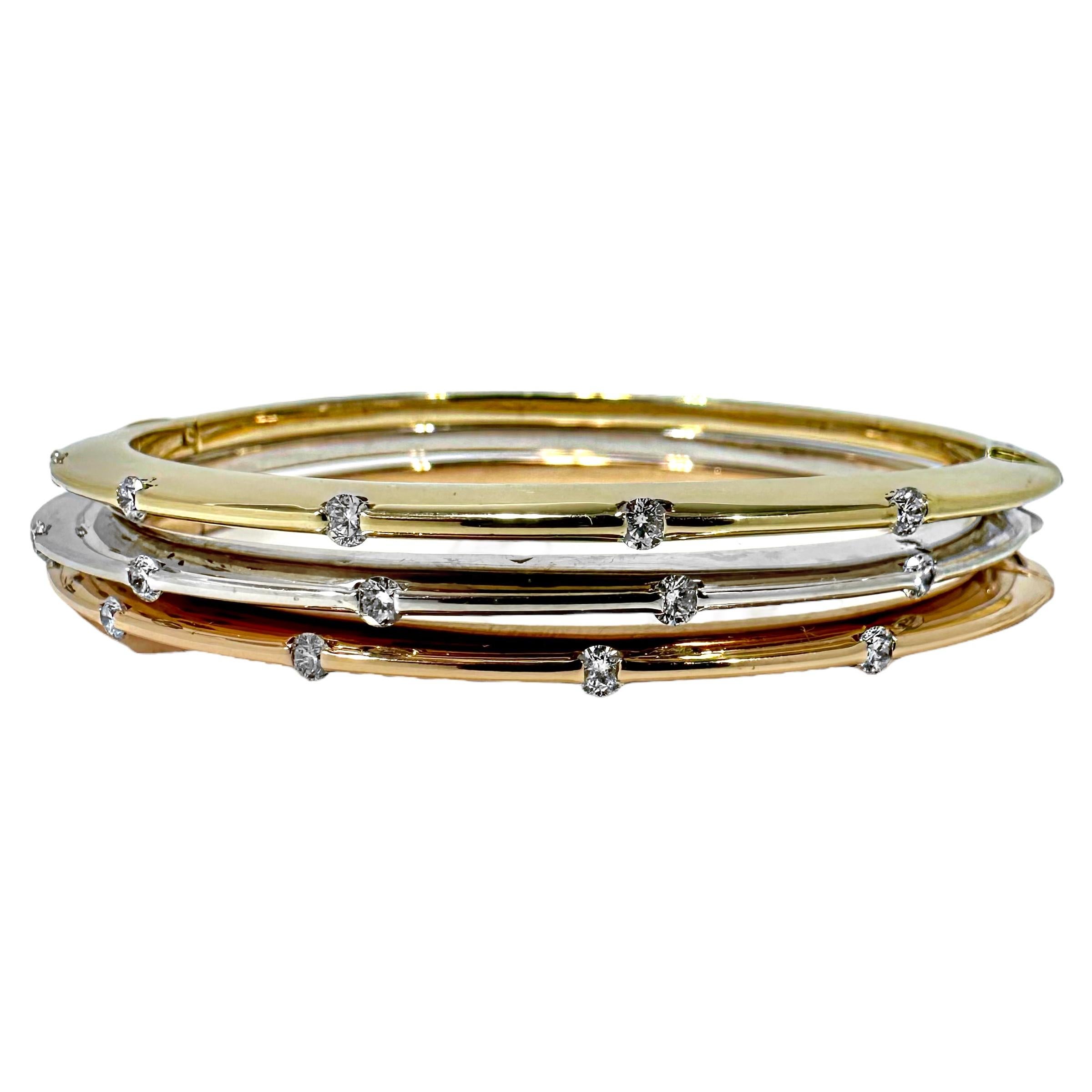 This exceedingly stylish and well crafted three piece set of Italian, 14k yellow, white and rose gold, hinged bangle bracelets are Gem-loc style, set with a total of fifteen modern round brilliant cut diamonds. Diamonds have a total approximate