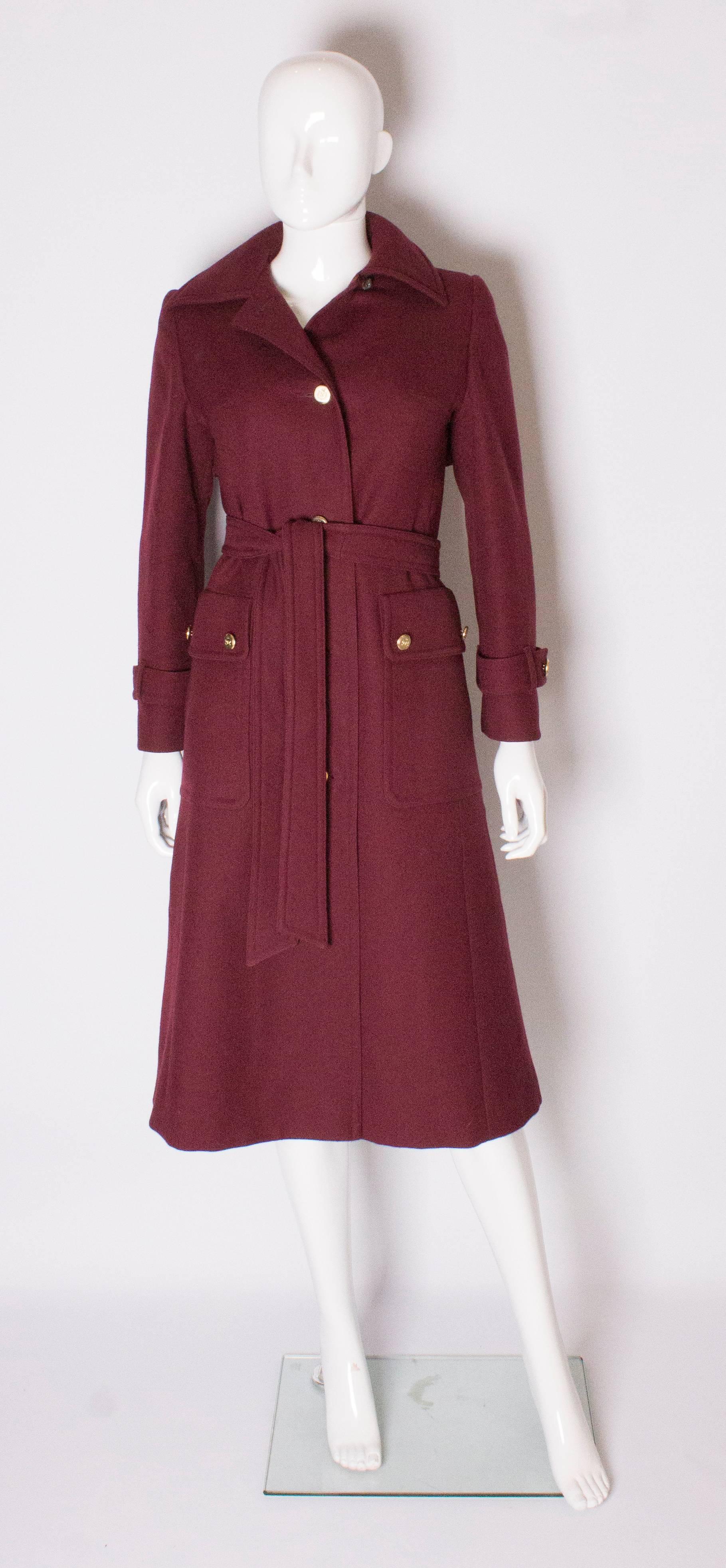 A great vintage coat for Autumn /Winter by Aquascutum for Harrods. In a burgundy colour wool, the coat has a 4 button opening , two large pockets on the front and a self tie belt. It is fully lined.