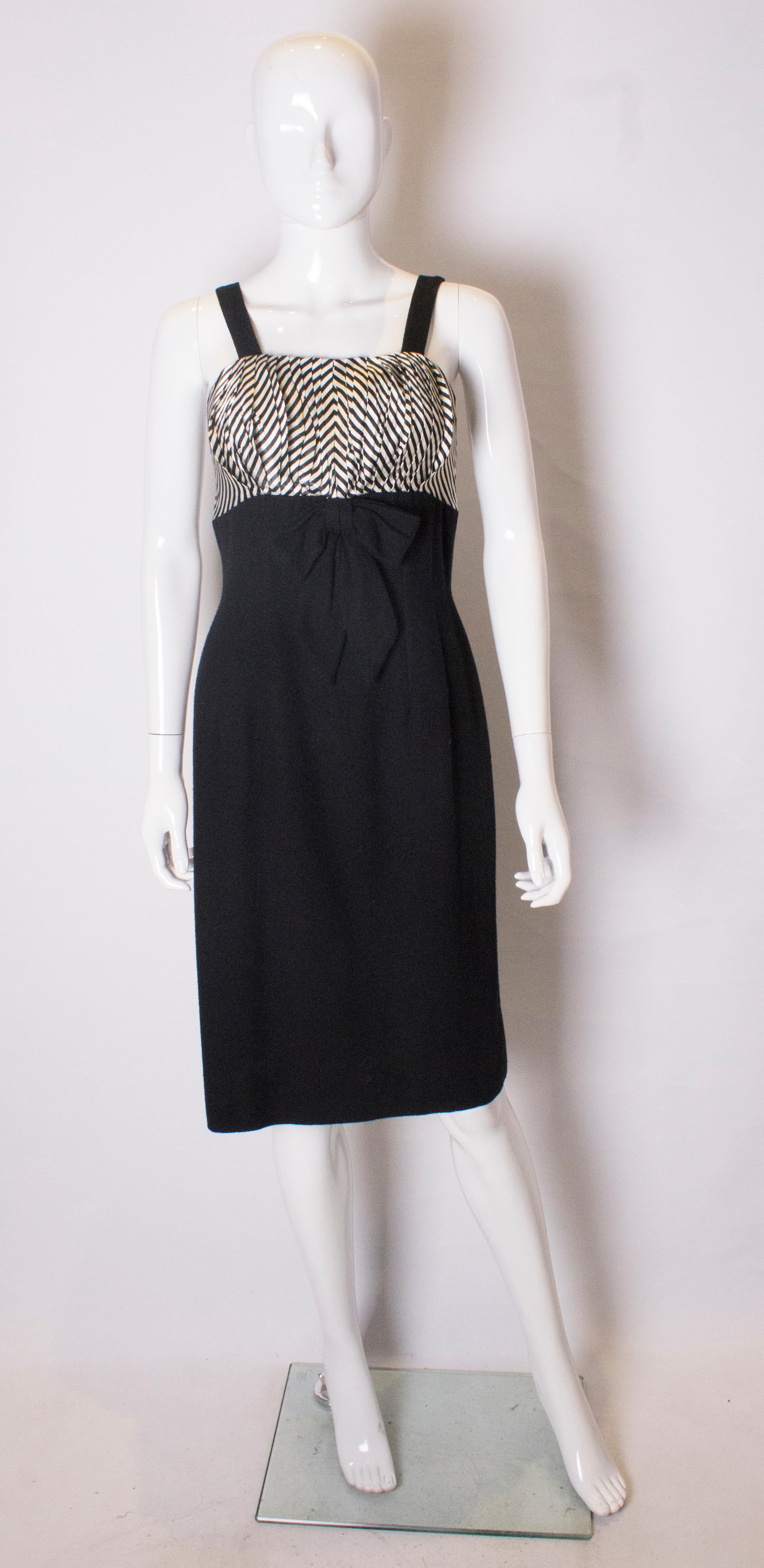 A chic vintage cocktail dress in black and white. The dress has a black body , and black and white bodice. It has a central back zip , and the bust area is lined.