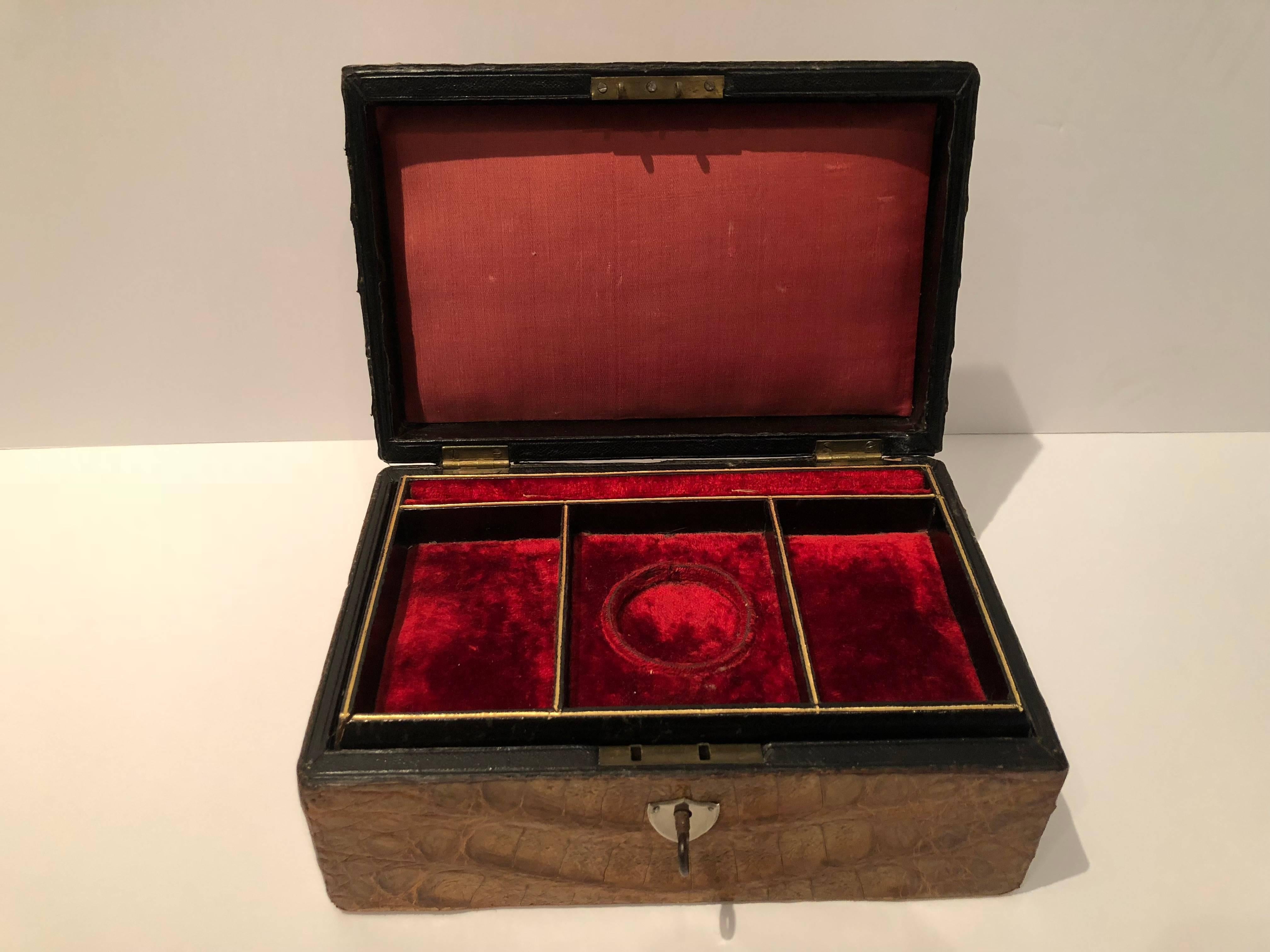 Chic vintage men's crocodile jewelry case in a rich shade of brown having a red satin lining with red velvet removable tray. The tray has sections for cuff links, watches, etc. The exterior hide is in excellent condition.