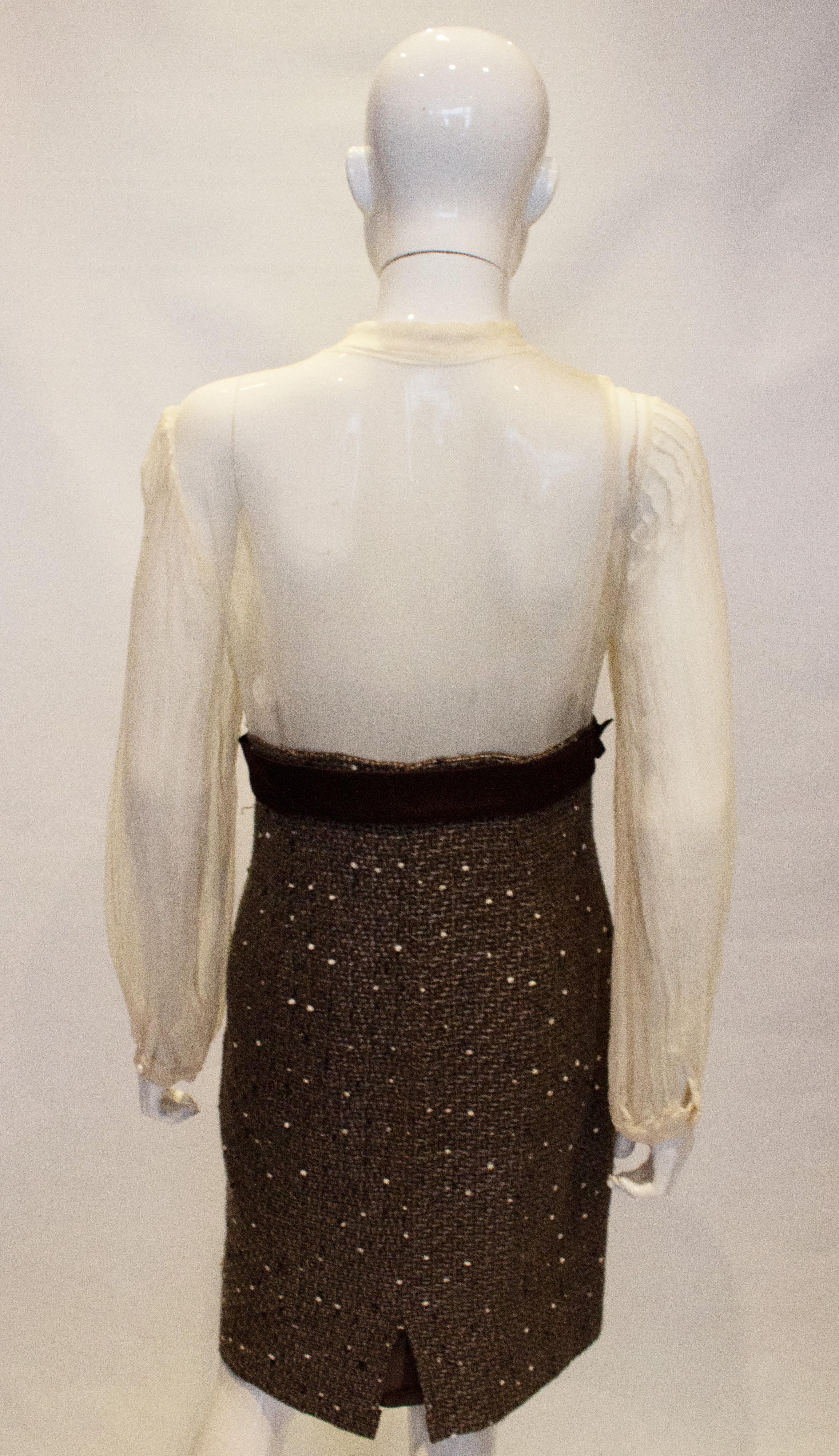 A wonderful vintage work to dinner dress. The top part is in a sheer silk chiffon decorated with pearls and lace. It has a mandarin collar and pleats on the sleave.  There is a brown silk bow and tweed skirt. The skirt is lined and there is a side