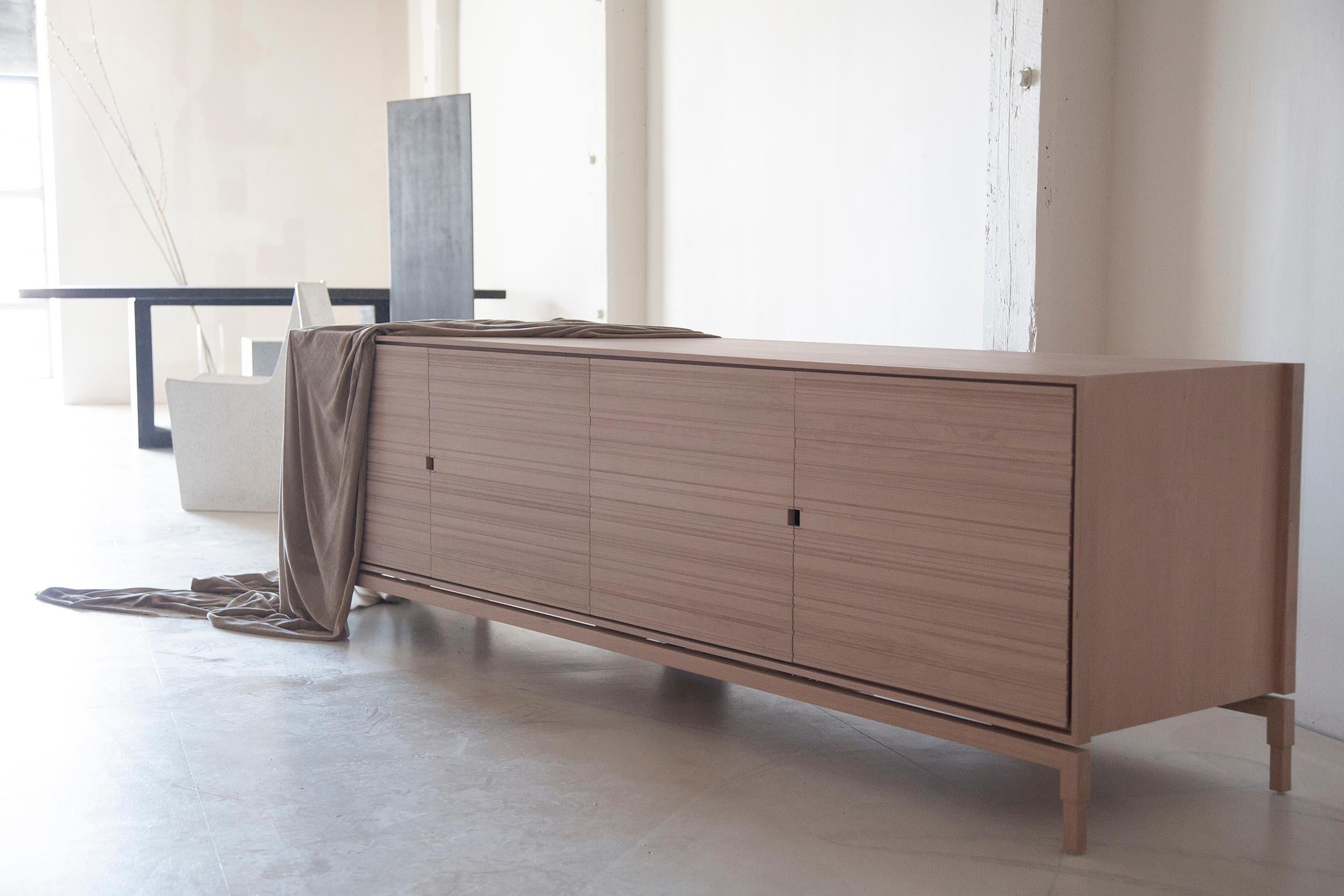 Chicago Credenza in Blush by May Furniture 
Finish: Blush;  Wood: Cherry
Details: 4 cabinet door credenza with hand cut kerf groove door fronts. 
Made in/ships from: Brooklyn, NY 11222
Standard size:  94.5