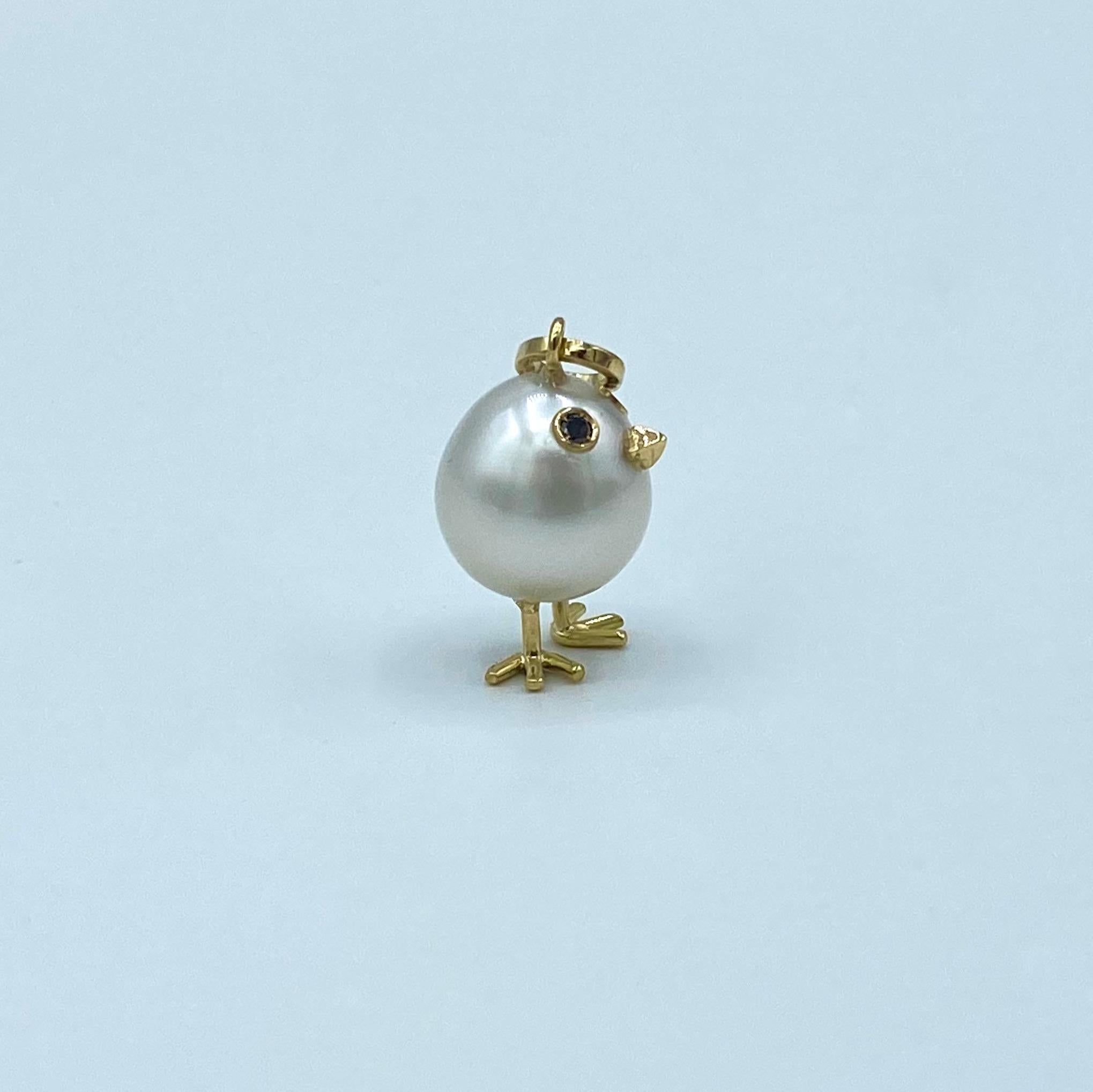 Chick Australian Pearl Black Diamond Yellow  18Kt Gold Pendant or Necklace
A oval shape Australian pearl has been carefully crafted to make a chick. He has his two legs, two eyes encrusted with two white diamonds and his beak. 
The 18KT gold is