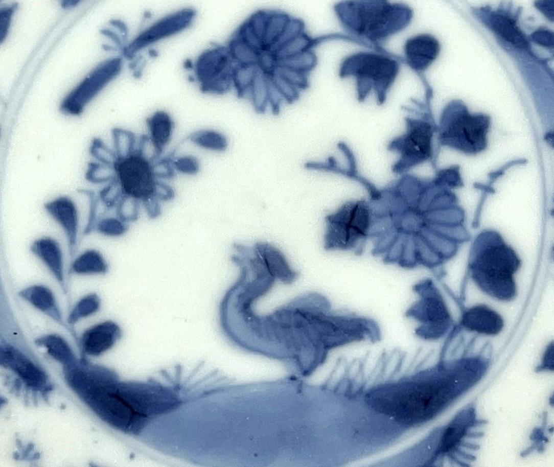 This fine piece of porcelain, a plate from the Qing Dynasty, is a testament to the enduring craftsmanship of Jingdezhen, the porcelain capital of China. It presents a classic blue and white aesthetic, with intricate botanical motifs arranged