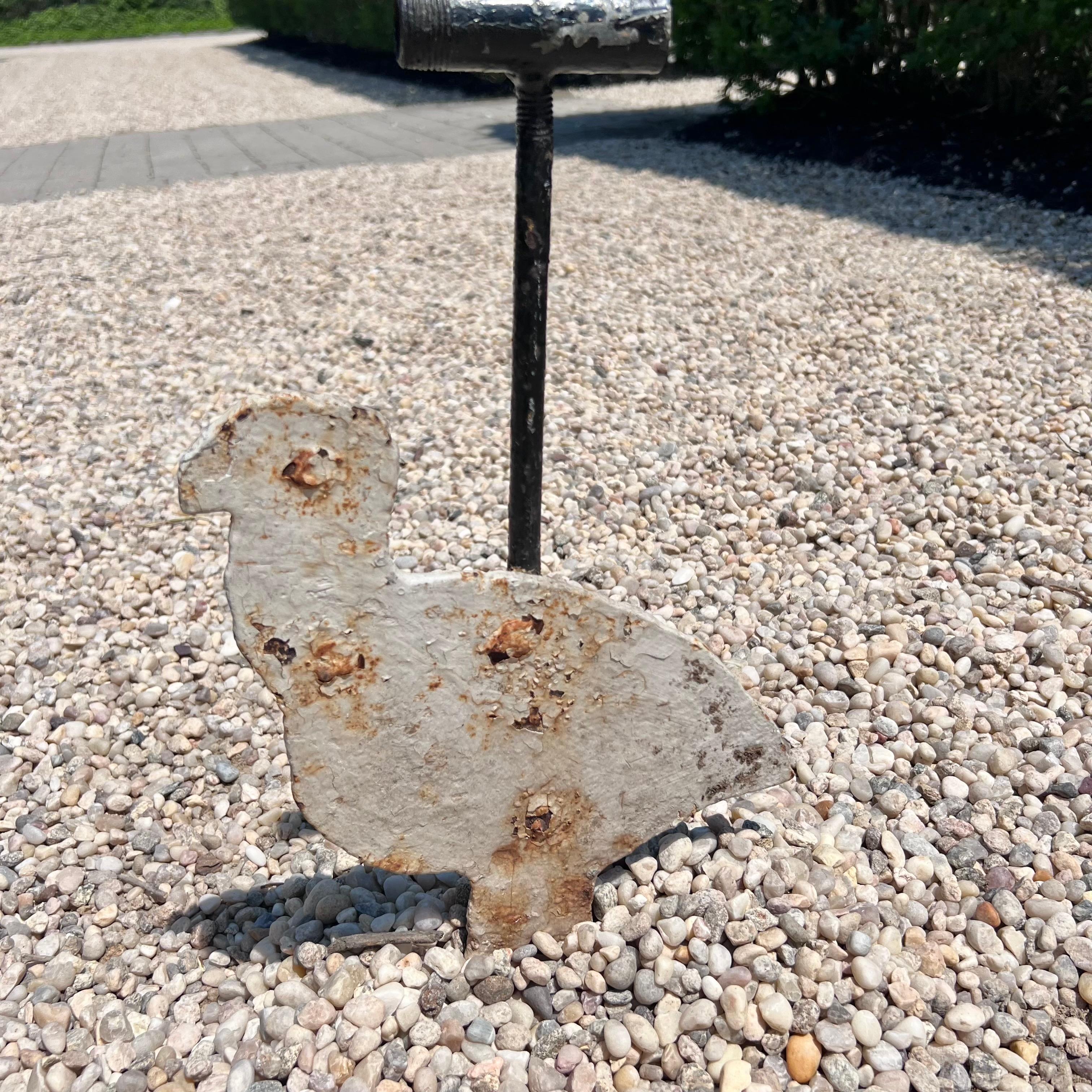 Very interesting heavy metal shooting target. Figure of a small chicken is attached to a metal post with a hollow tube at the top which a cable would run through suspending this target in the air. Figure is on a hinge so when you hit the target, the