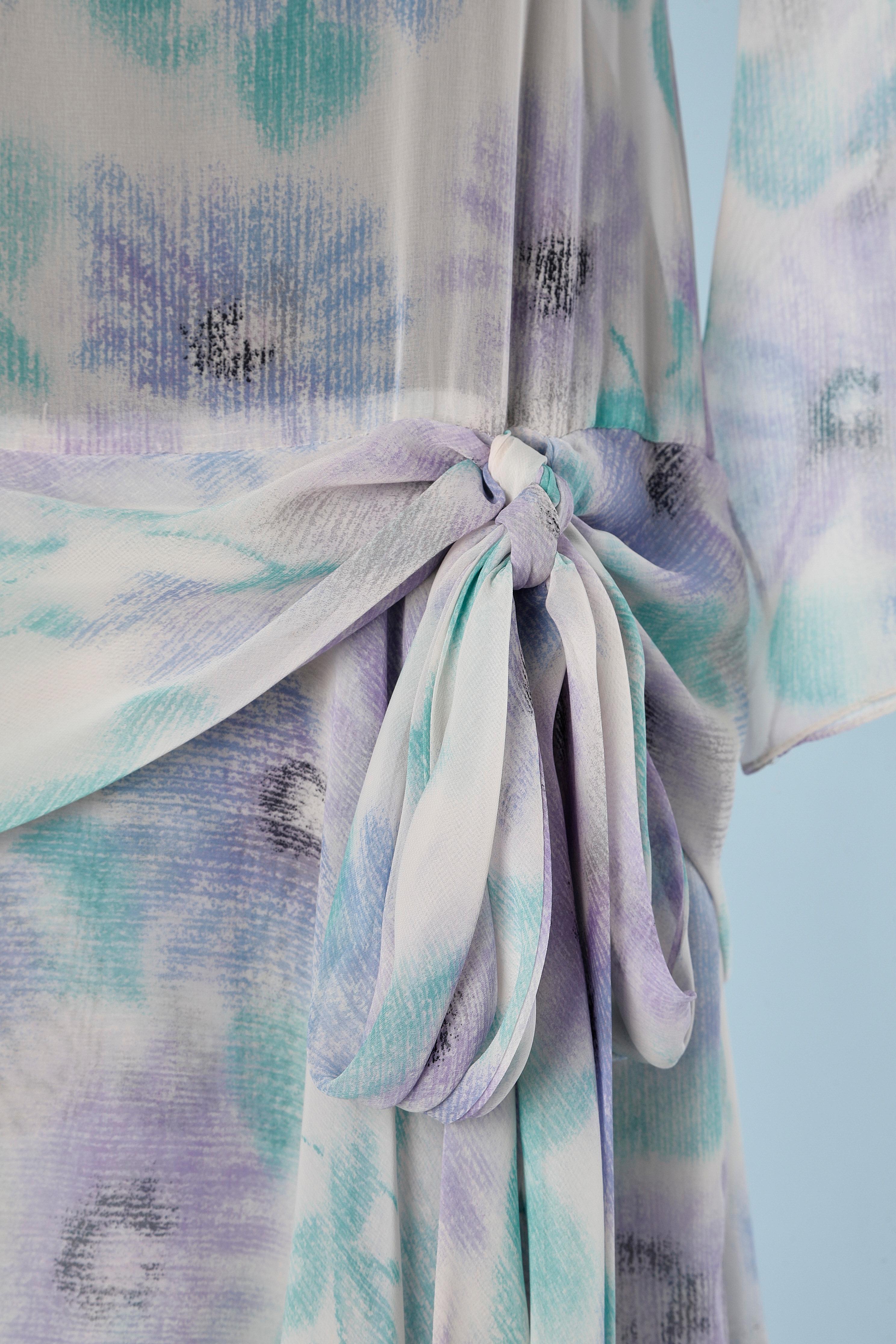 Robe de cocktail en mousseline avec imprimé de fleurs pastel et nœud sur le côté gauche de la taille. Pas d'étiquette de tissu, probablement en polyester. Un bouton et une boutonnière en haut au milieu du dos. 
TAILLE L 