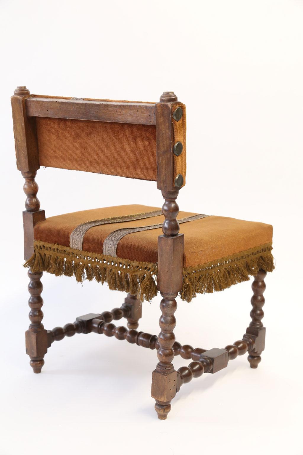 Child-size French chair in Louis XIII style: hand carved walnut in pegged construction with mortise and tenon joints. Almost bobbin-style turned legs and stretcher. Dates to the late 19th century and upholstered in antique fabric.