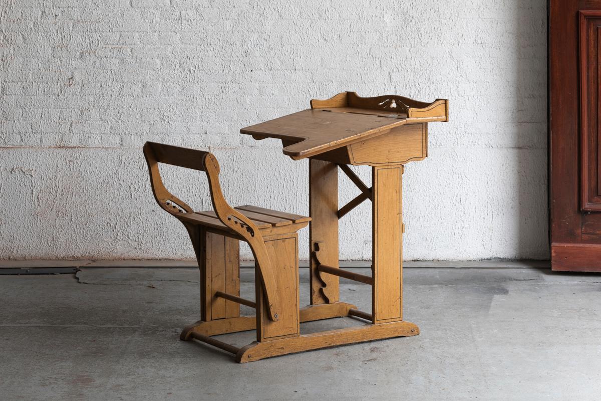 Children’s desk designed and produced in the Netherlands, art deco period. The chair and desk are connected to eachother, and feature a solid wooden base. The desk top is a fold-up door for storage space, including a chalkboard. Using marks as shown