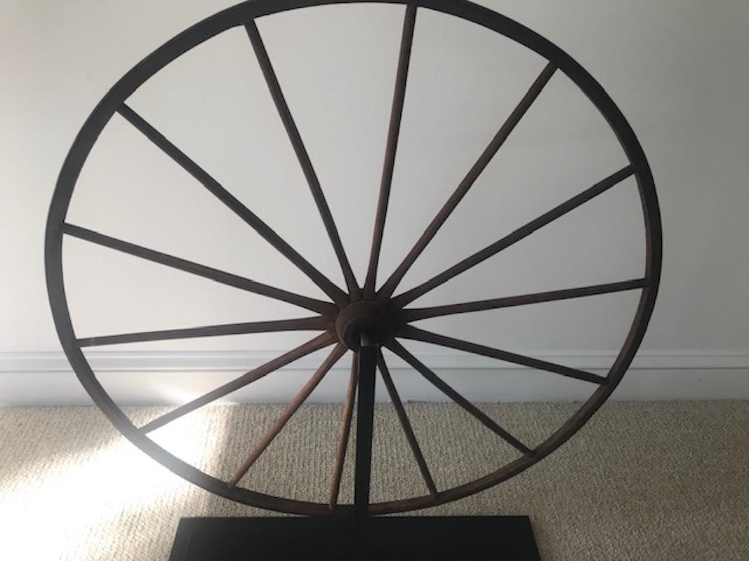 Bring some folk art into your home with this period wooden wagon wheel. The diminutive size suggests that it was originally on a child's wagon. It has been expertly mounted a custom steel stand, allowing it to be placed on a fireplace, mantle or