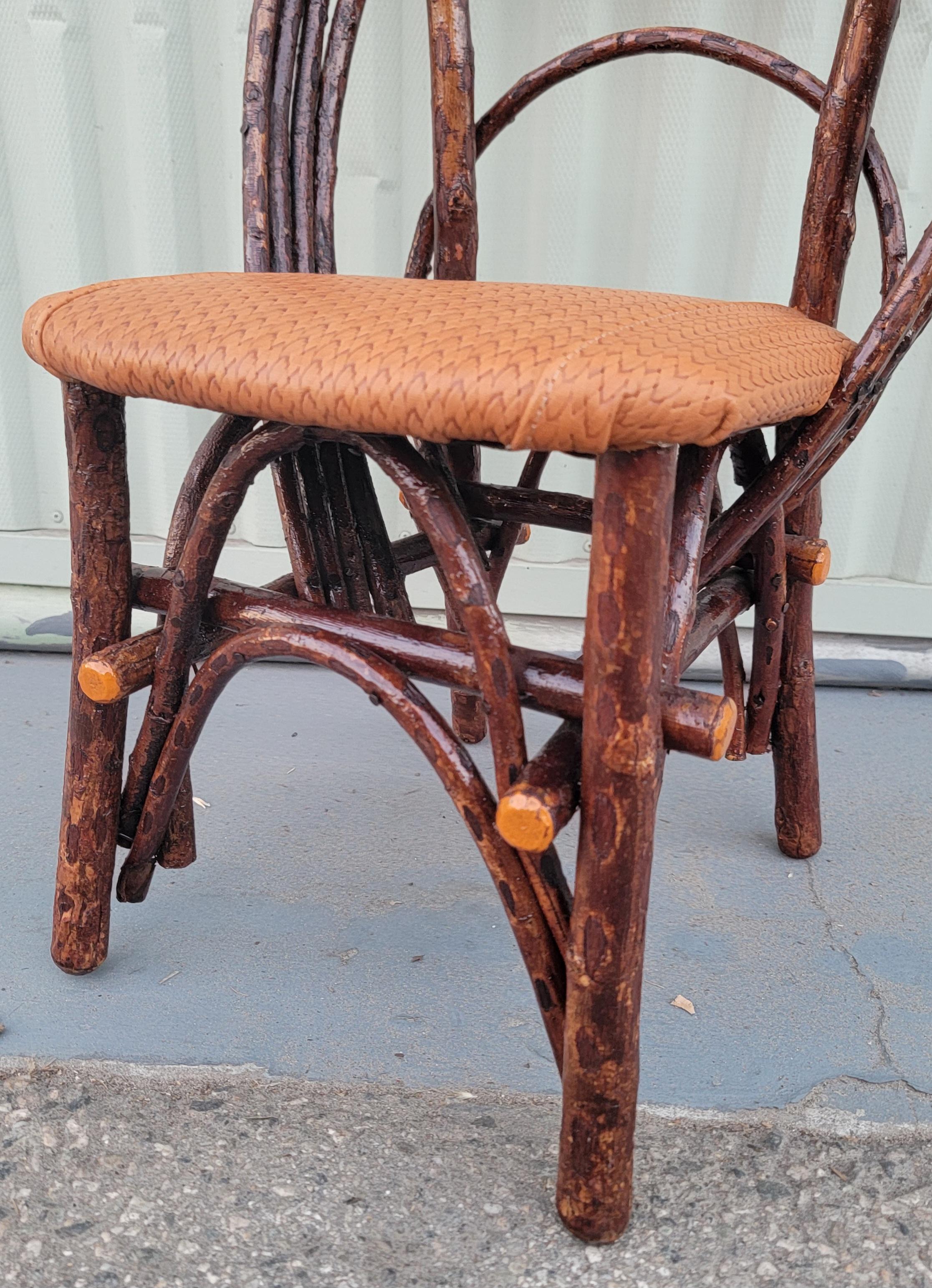 Early 20thc hand made folky twig Child's chair with leather seat.This chair is in very sturdy condition.The trim of the twigs are painted original  orange paint.This is a very strong and fine condition.