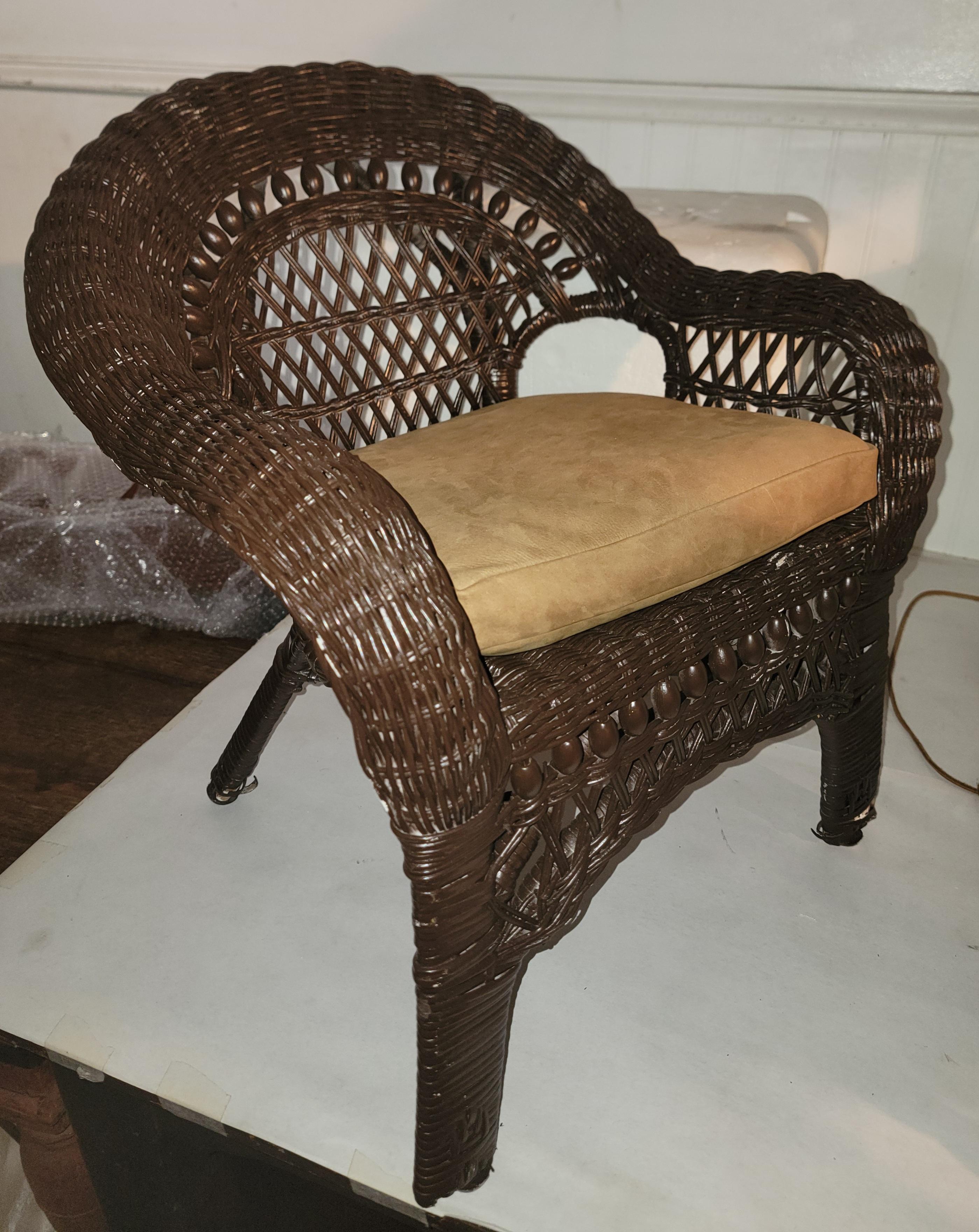 Cette chaise d'enfant en osier est très originale et a été repeinte avec une couche de protection pour l'extérieur. Le coussin d'assise est fait sur mesure en cuir / suède.