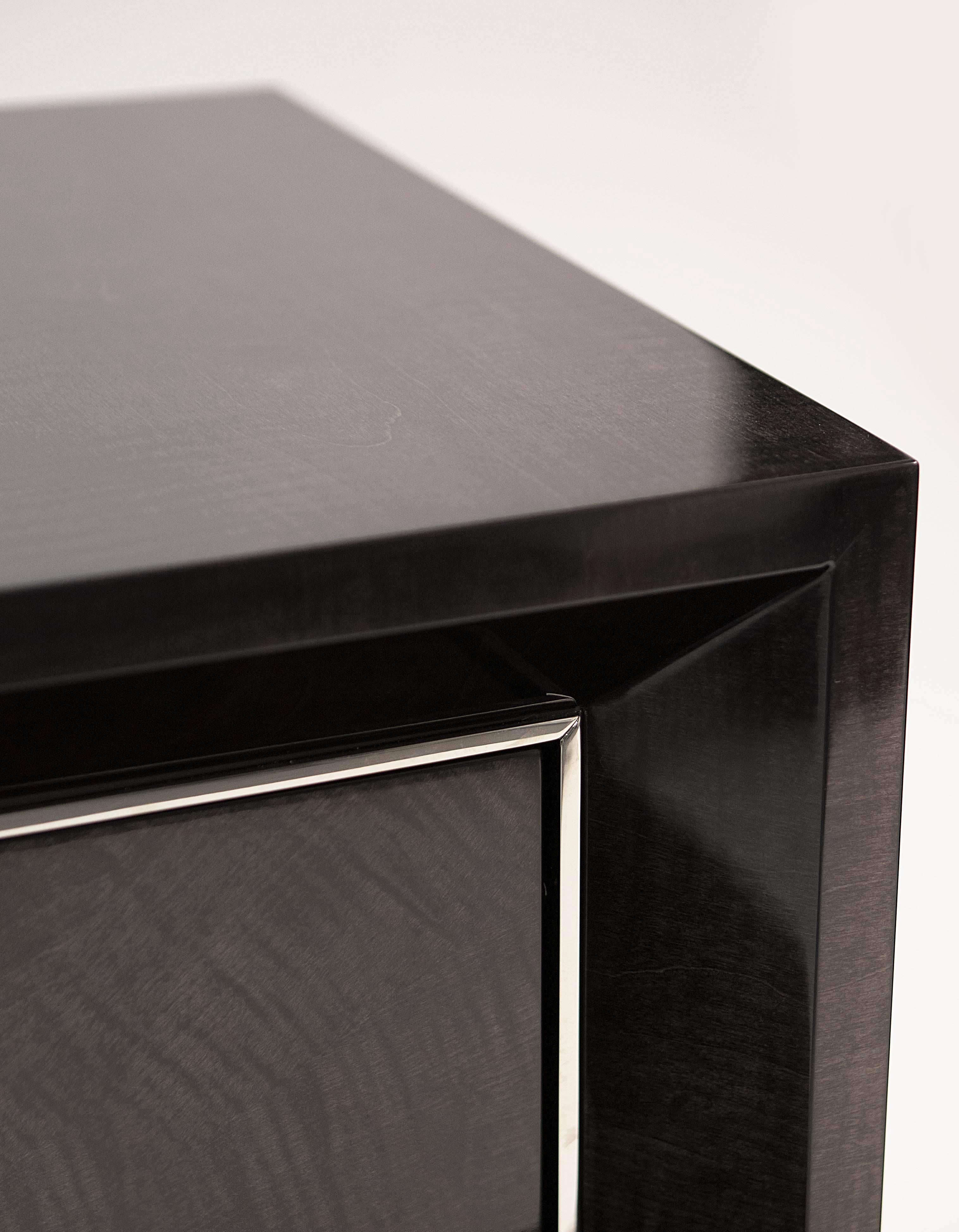 A smart side cabinet finished in sycamore black and polished nickel.

Smart and refined storage with a luxurious polished nickel moulding opening to reveal an interior in matte sycamore grey with two adjustable shelves.

There is the option of a