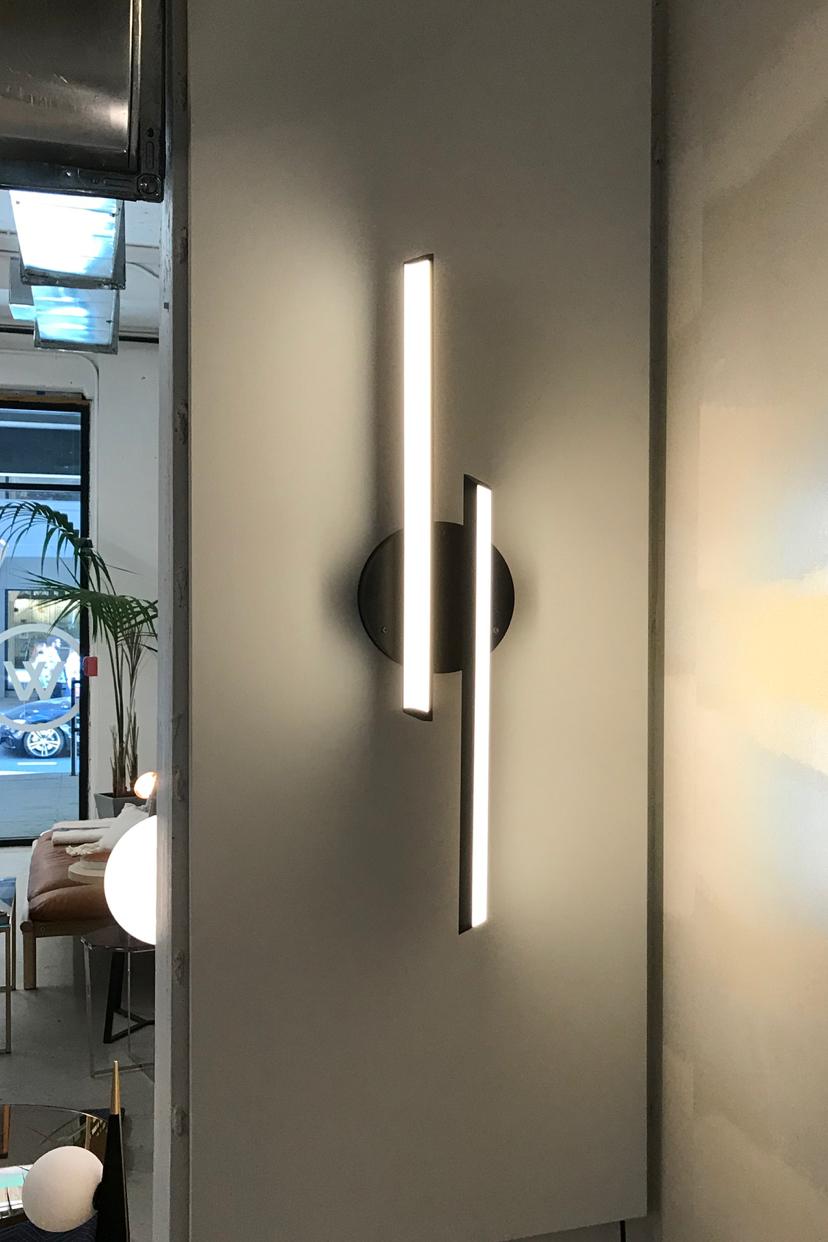 CHIME CONTRA sconce is inspired by the harmonious sound of resonating bells. CHIME CONTRA uses two opposing bars of soft warm light, centered over a disc backplate. Available in two sizes and can be wall mounted or flush mounted on the ceiling.
