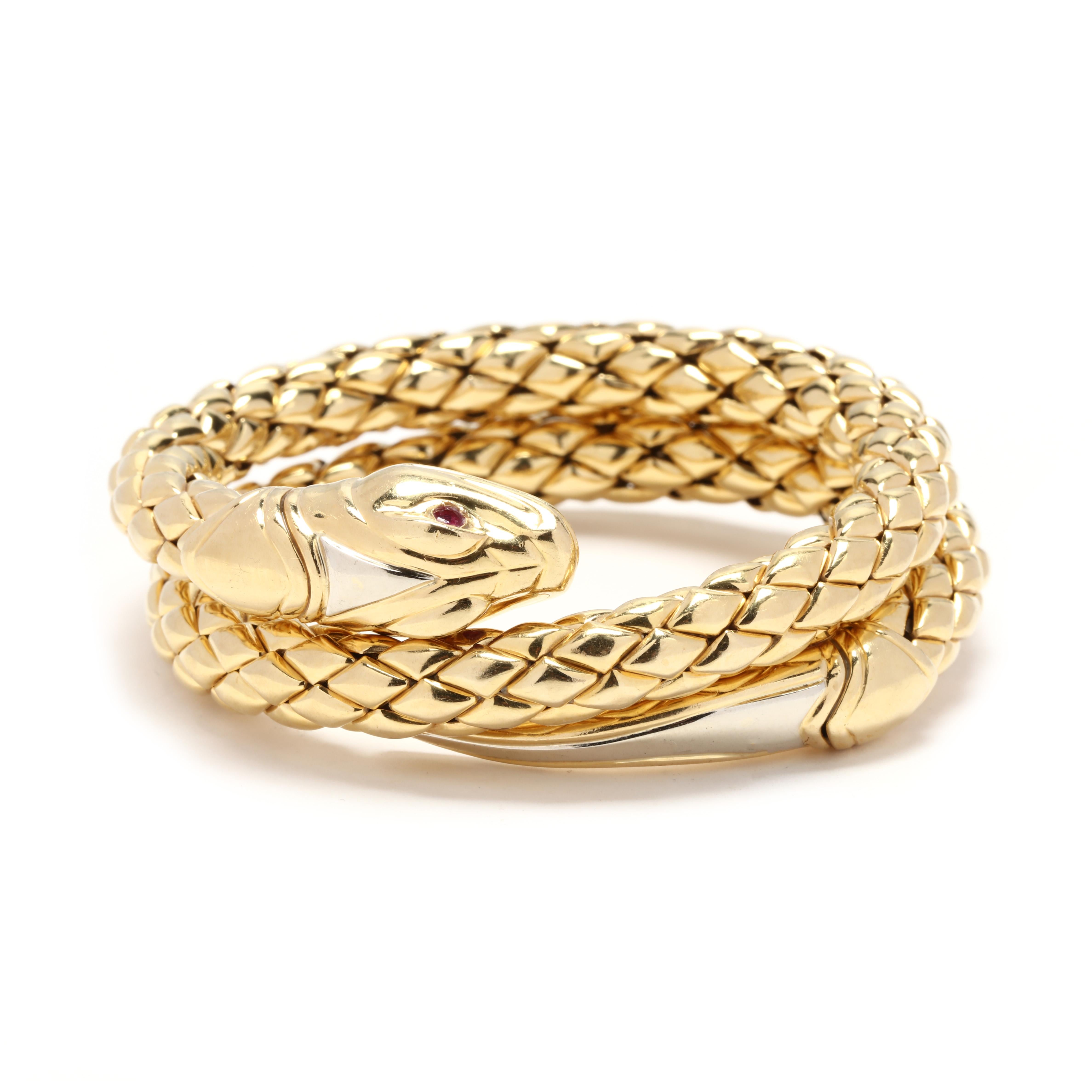 An 18 karat yellow gold and ruby double coil snake bracelet by Chimento. This double wrap bracelet is made of solid gold, that is flexible so that it wraps around your wrist. With a snake hear motif at one end with round cut ruby eyes, a lozenge