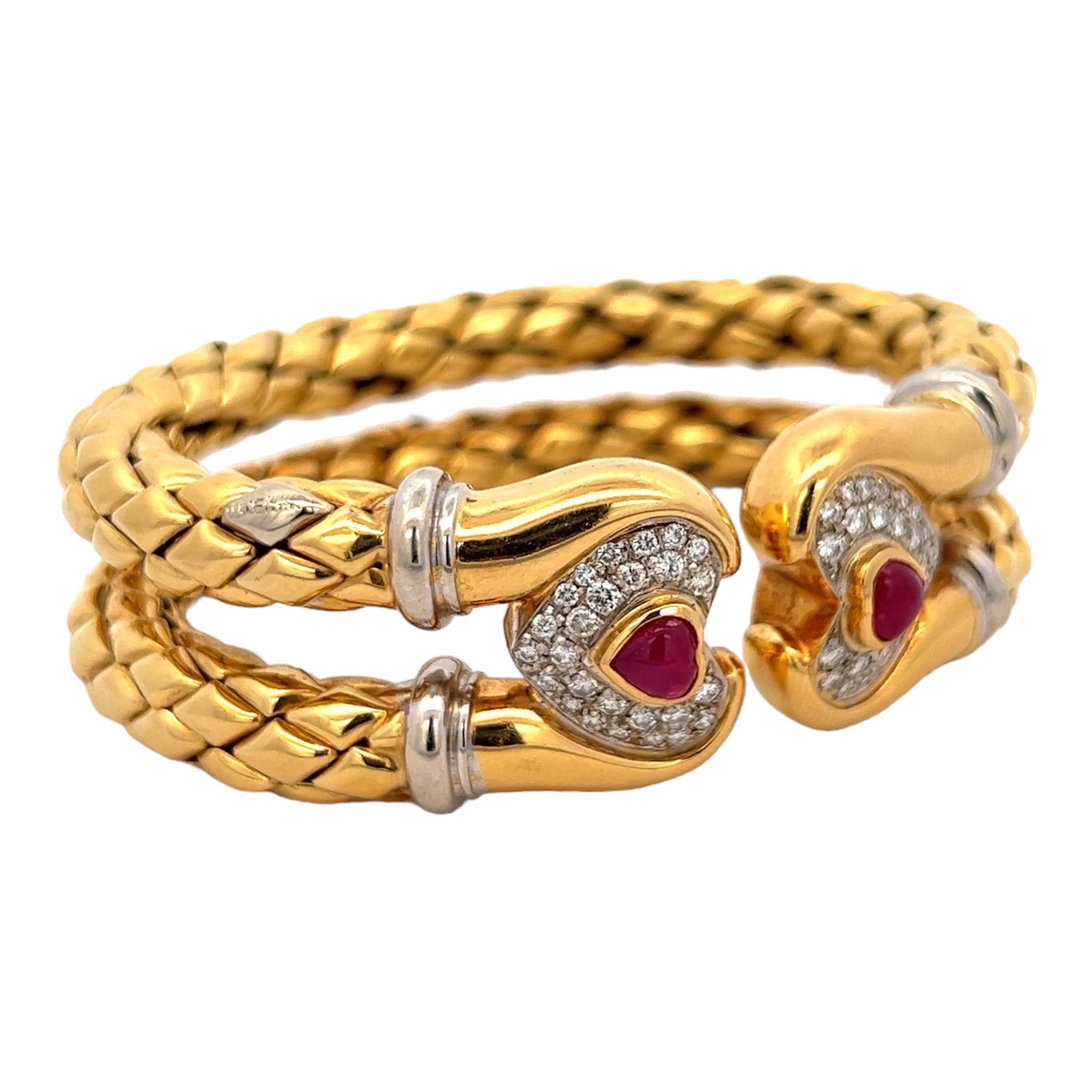 Diamond and ruby cuff bracelet by designer Chimento. The cuff features two rows of flexible woven 18 karat yellow gold with diamond and ruby heart endcaps. The 52 round brilliant cut diamonds weigh approximately 1.50 CTW and are graded G-H color and