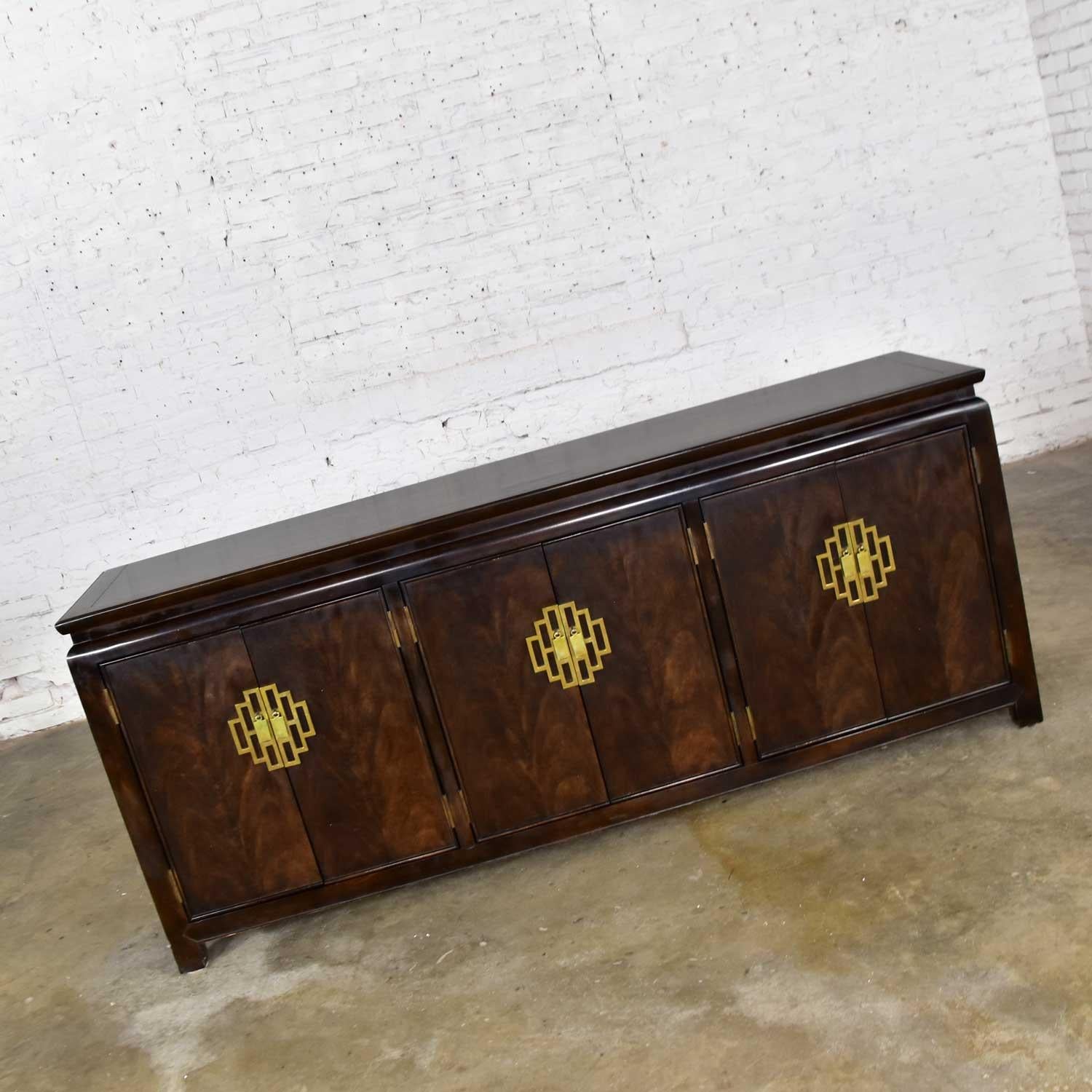 Handsome Hollywood Regency chinoiserie buffet or credenza designed by Raymond K. Sobota for his Chin Hua Collection for Century Furniture. Comprised of dark ebonized ash with burl wood and brass accents and pulls. This credenza is in wonderful