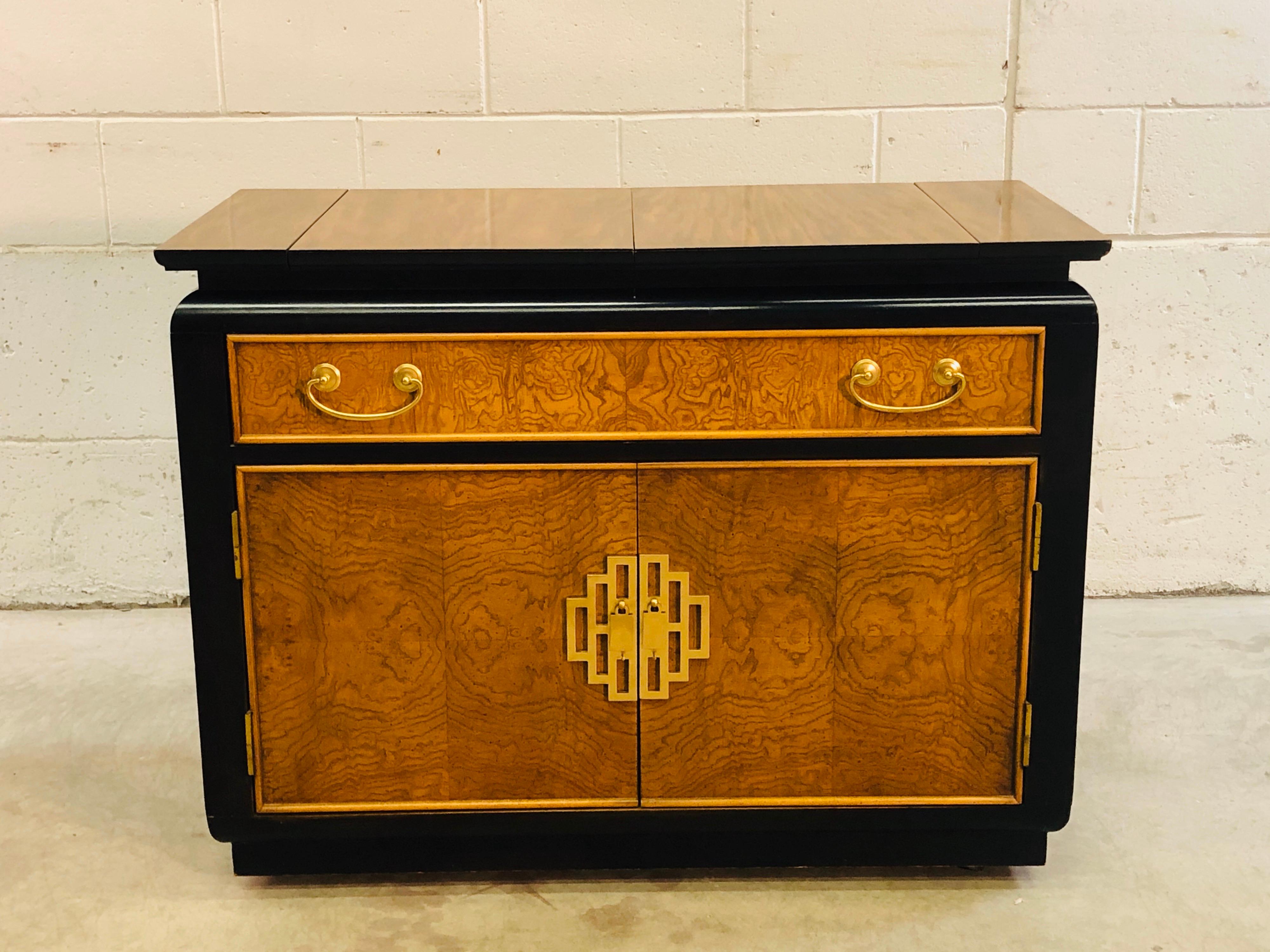Vintage 1970s rolling bar cart or sideboard designed by Ray Sabota for Century Furniture. The cart has a burl wood inset on a ebonized base and great Asian Modern brass handles. Marked in drawer. Excellent condition. Top fully open is 58” L.