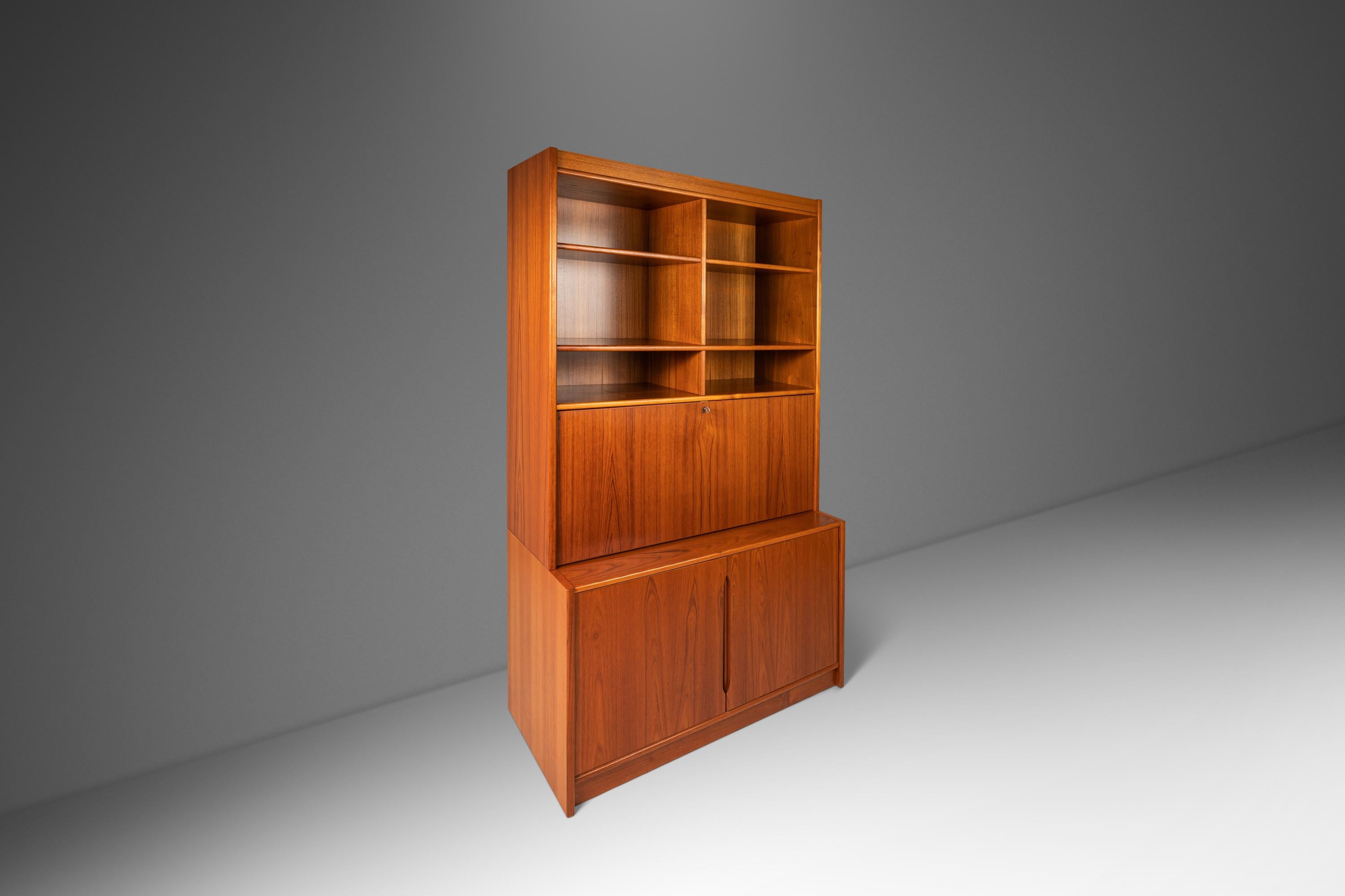 Equal parts elegance and functionality this gorgeous Danish Modern display cabinet is as versatile as it is beautiful. Featuring a drop-down secretary desk top with functioning lock and skeleton key this cabinet can serve both as a convenient desk