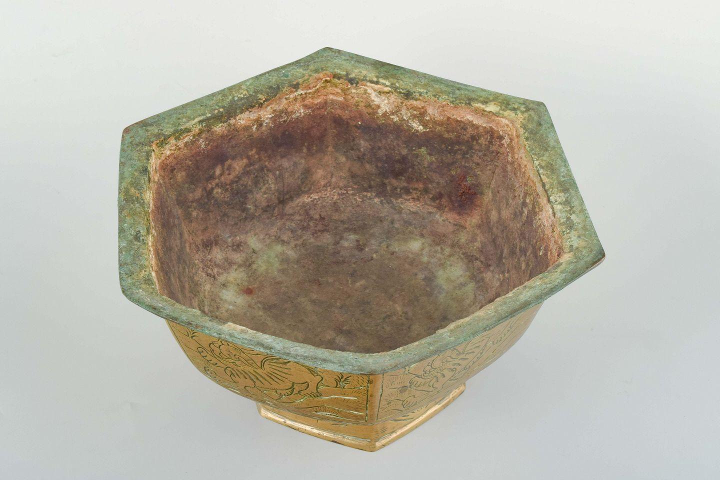 China, vergoldetes Bronzegefäß, Ming-Dynastie (Xuande-Marke, 1426-1435), später, 18./19. Jahrhundert.
Sechseckiges Gefäß aus vergoldeter Bronze, verziert mit eingravierten Tiermotiven in Tafeln. Die Unterseite trägt das vierstellige Xuande-Zeichen