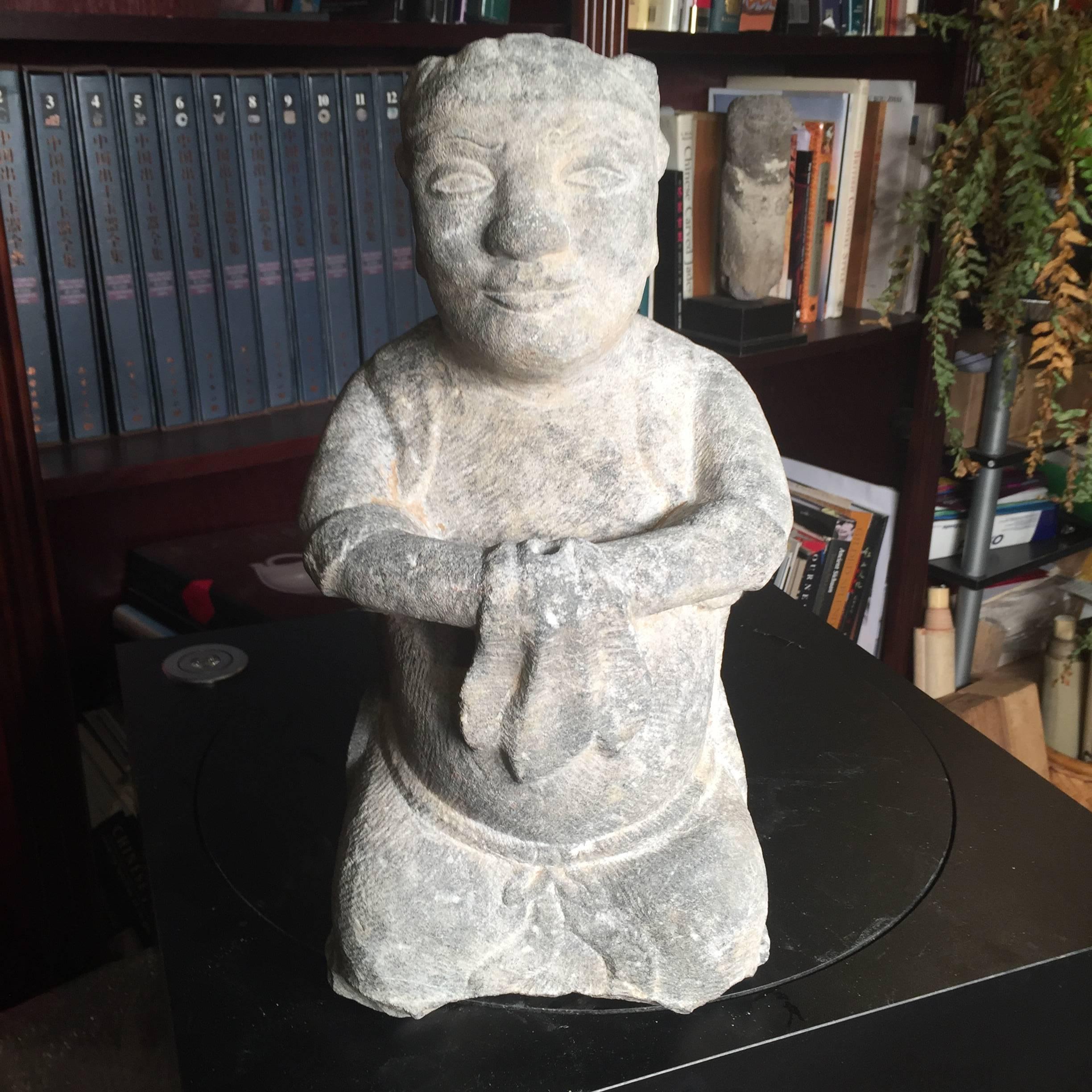 China, a large hand carved effigy of a seated attendant, limestone, Qing dynasty 1644-1912. 

Dimensions: 15.5 inches tall and 7.5 inches wide and 5.5 inches deep

The hand carved figure shown on its haunches with a naturalistic servitude