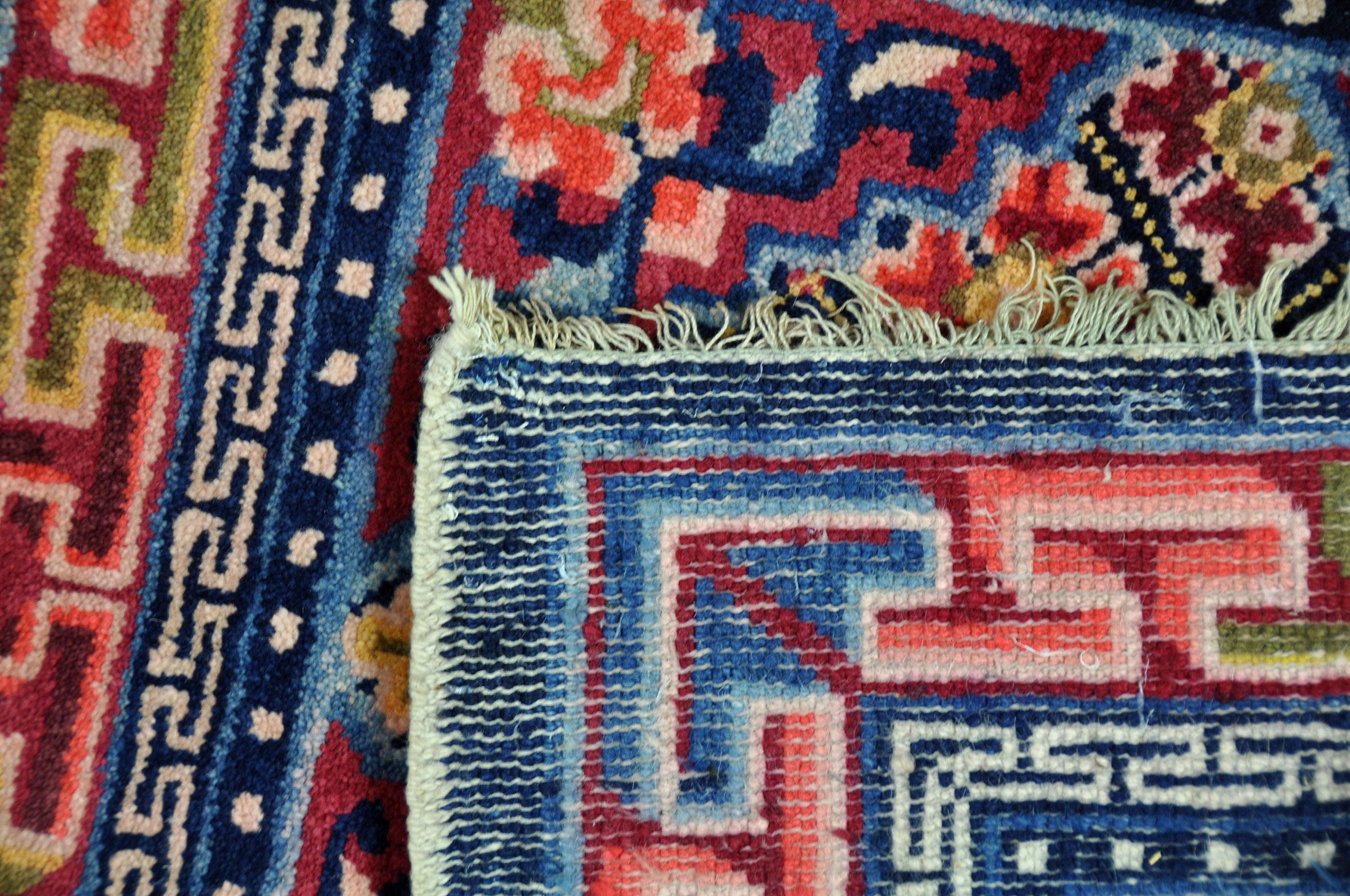 Eccentric square Chinese rug where bright colors and ingenious design play a leading role.
Typical of these Chinese rugs is the use of spatial shadow effects. This effect can certainly be found in the Meander motif in the edge of this fine hand