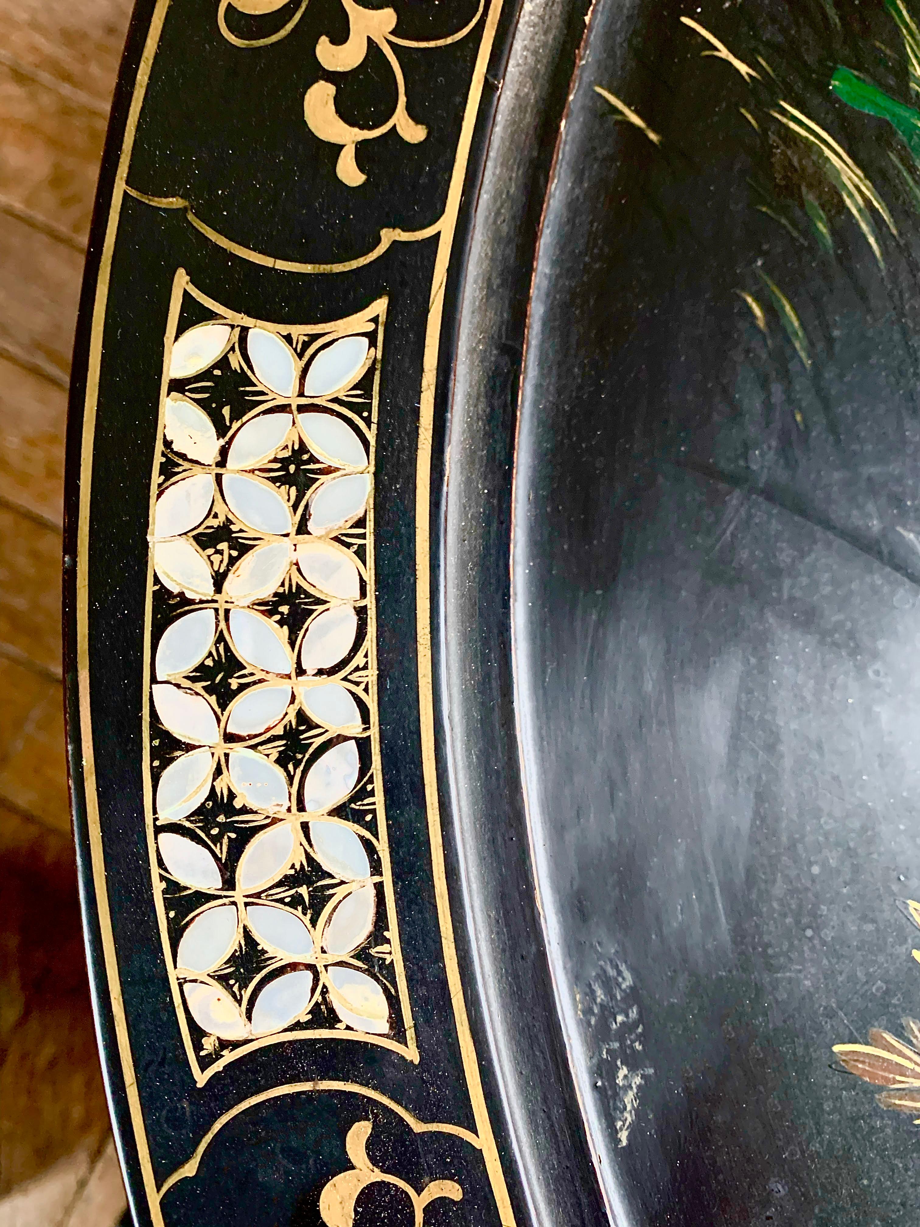 Pretty coffee table in black Chinese lacquer. The feet are slightly curved and adorned with golden arabesque patterns at the bottom and top. The entablature and the apron of the top are also decorated with gilt arabesque motifs. The magnificent tray