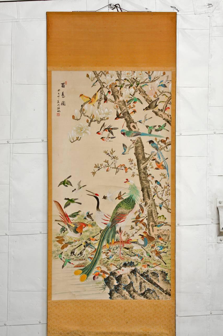 Impressive Chinese hanging scroll painting depicting 100 birds with a phoenix gathered at a flowering magnolia tree. Intricately detailed with a rainbow of vivid colors. Signed and stamped on top right with two seals. The 100 bird and phoenix image