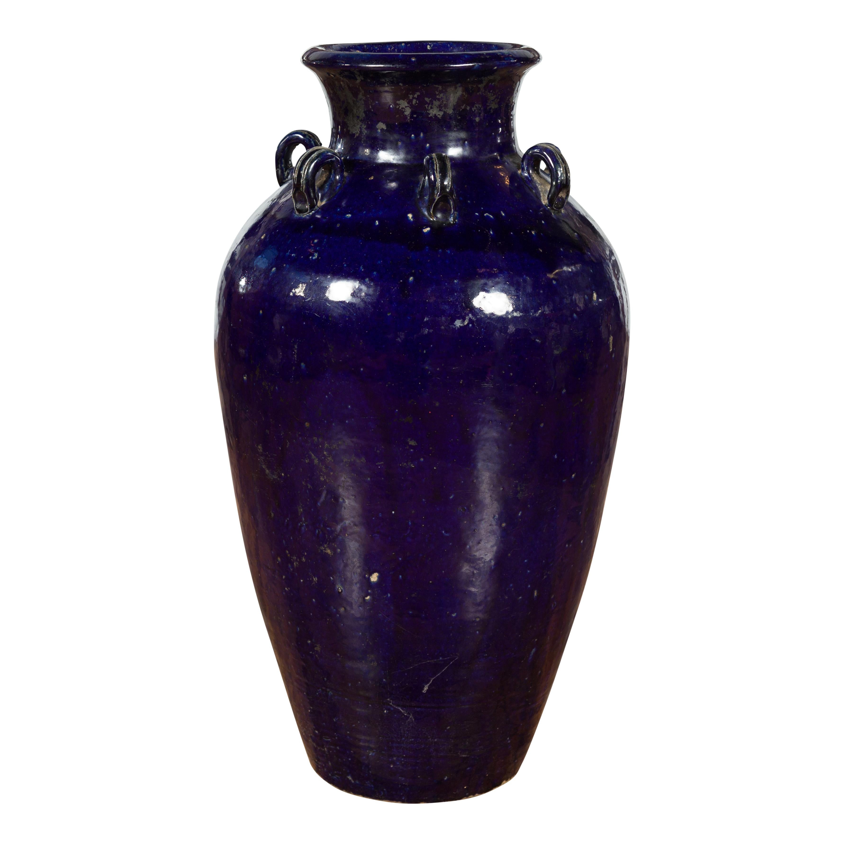 A large Chinese cobalt blue Martaban jar with petite loop handles. Created in China, this large antique cobalt blue Martaban vase is adorned with a series of petite loop handles through which a rope would have been passed to secure a top. The