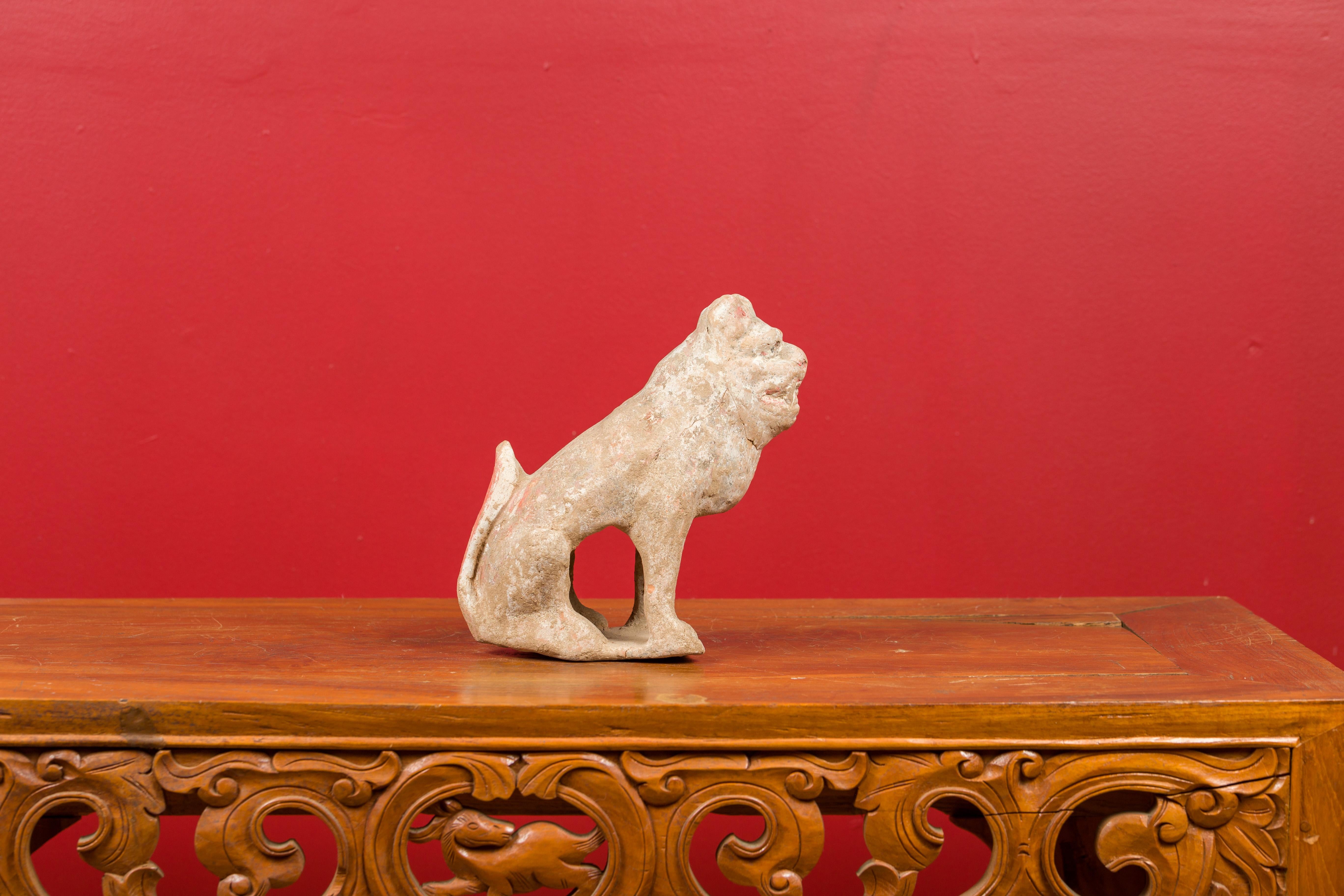 A Chinese Qing dynasty terracotta dog Mingqi sculpture from the 18th century, with traces of original pigmentation. Created in China during the 18th century, this terracotta sculpture showcases a dog depicted in a seated position, his tail nicely