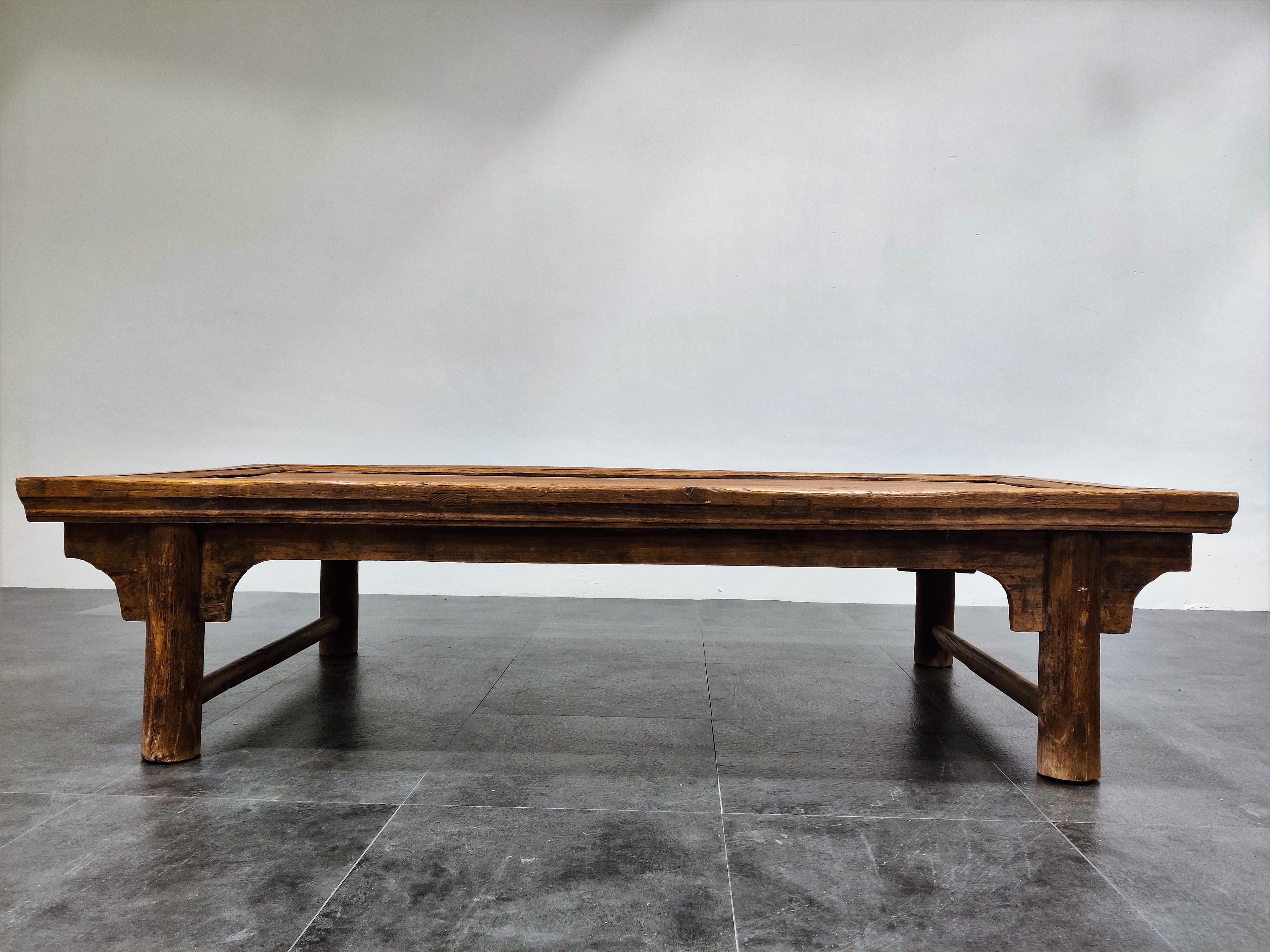 A Chinese elm and pine low table or Kang, probably Shanxi

The oblong top with a void panel and moulded deep edge above massive square legs and stretchers.

Such tables were also used as a daybed and not only as a space to drink or even
