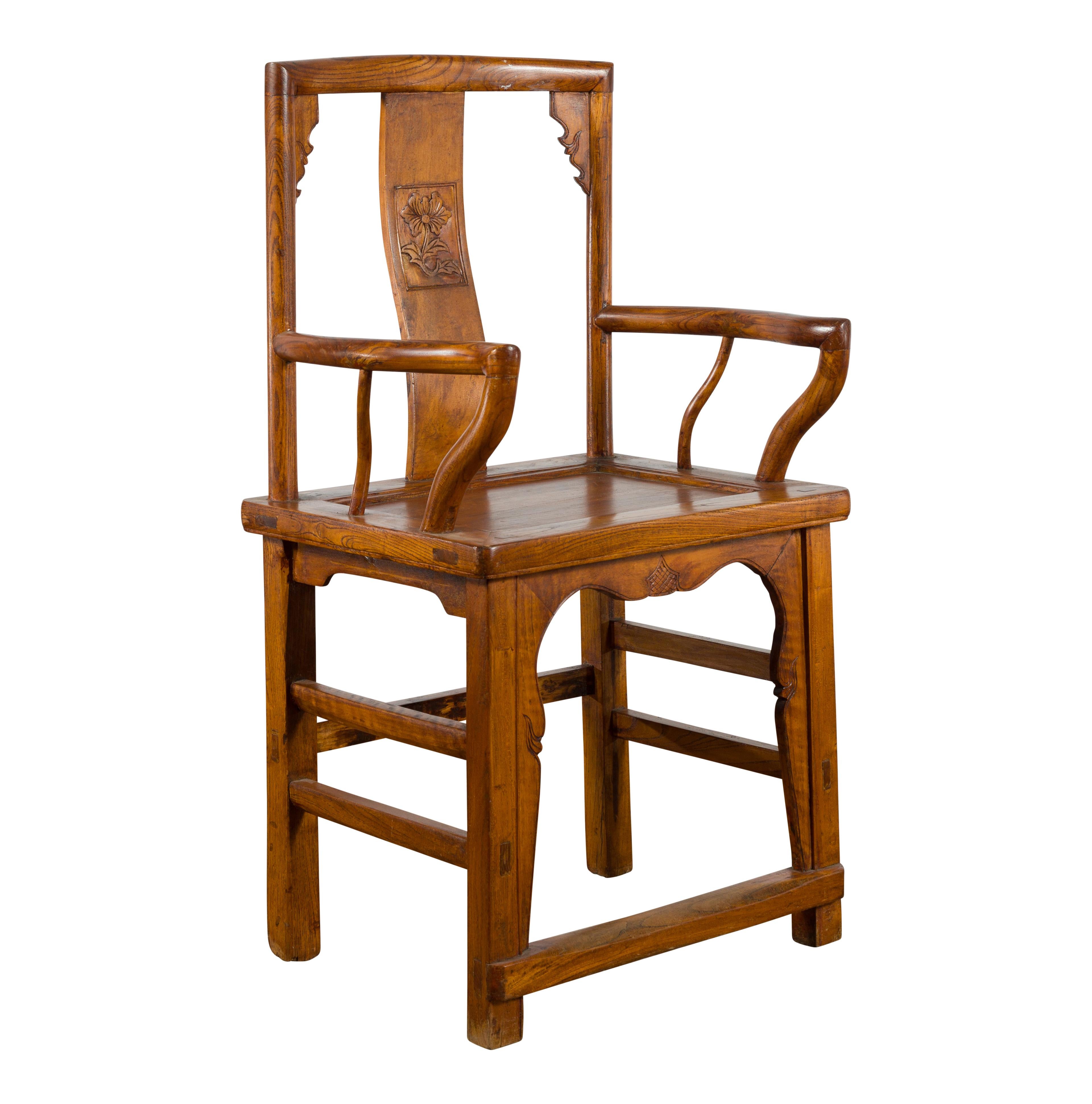 A Chinese Qing Dynasty period wooden armchair from the 19th century, with hand-carved motifs, serpentine open arms and straight legs with stretchers. Created in China during the Qing Dynasty, this chair features an open wooden back, adorned with a