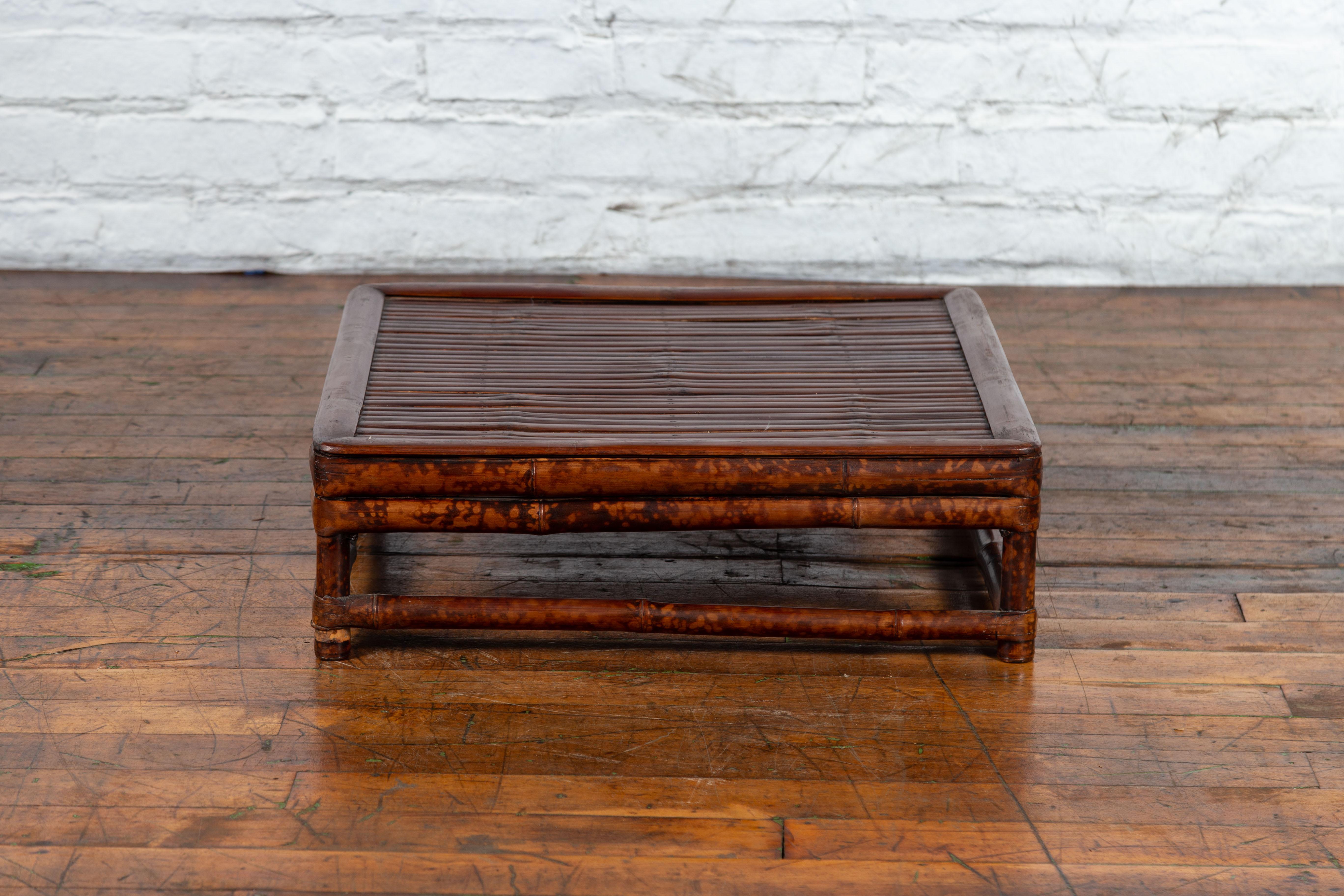 A Chinese Qing Dynasty bamboo low coffee table from the 19th century, with slatted top. Created in China during the Qing Dynasty, this low bamboo coffee table features a square slatted top sitting above four straight legs connected to one another