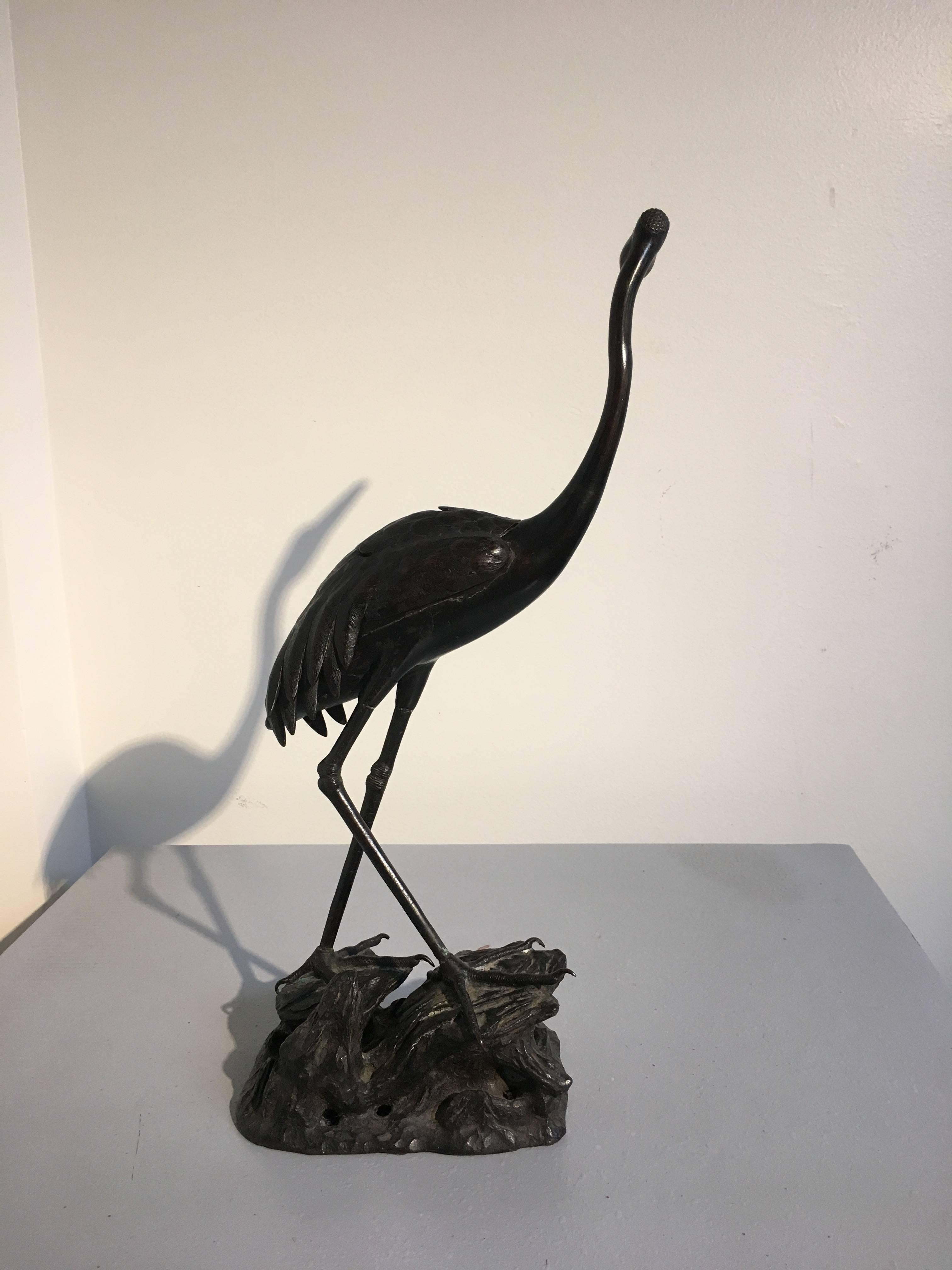 An unusual Chinese bronze censer in the form of a crane, Qing dynasty, late 19th century. 
The noble bird is portrayed with a strong sense of motion - standing in a walking stance upon a rocky outcrop with wings folded against its body, its long