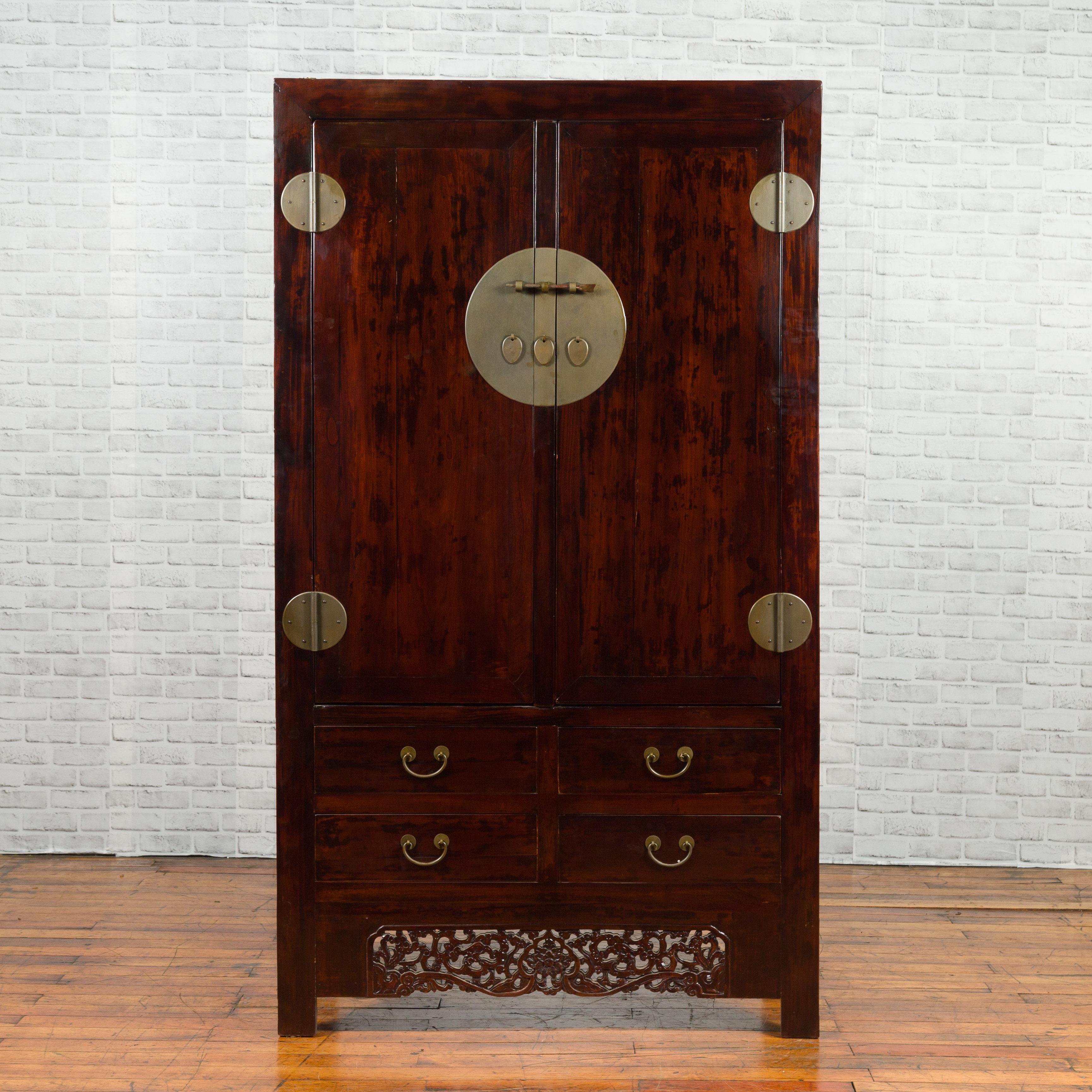 A Chinese Qing Dynasty period brown cabinet from the 19th century, with round medallion brass hardware, carved apron and four drawers. Created in China during the Qing Dynasty, this cabinet features a linear silhouette perfectly complimented by a