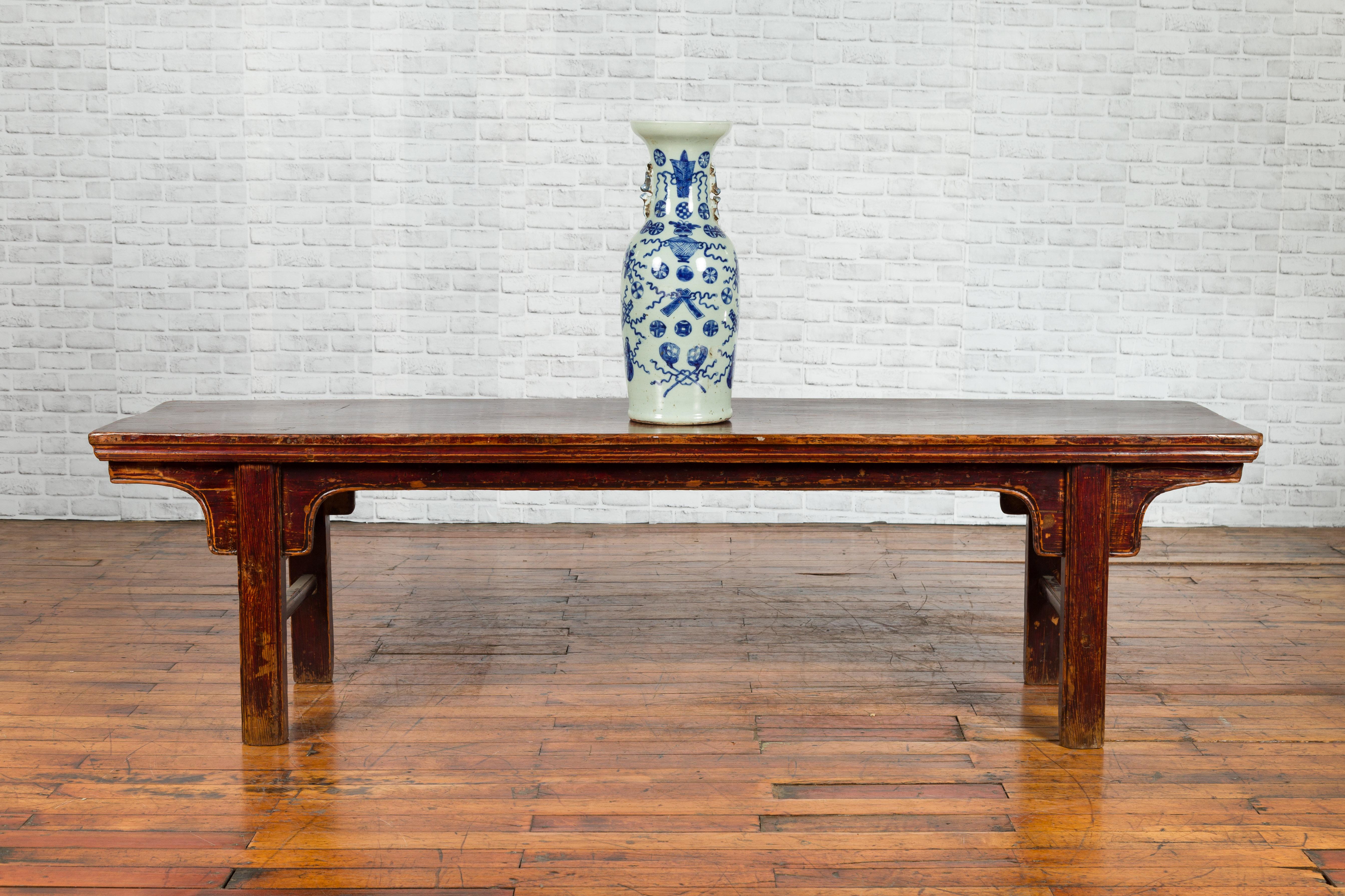 A Chinese Qing Dynasty period coffee table from the 19th century, with nicely distressed patina. Created in China during the Qing Dynasty, this low table, originally used as a bench, features a rectangular single plank top sitting above a simply