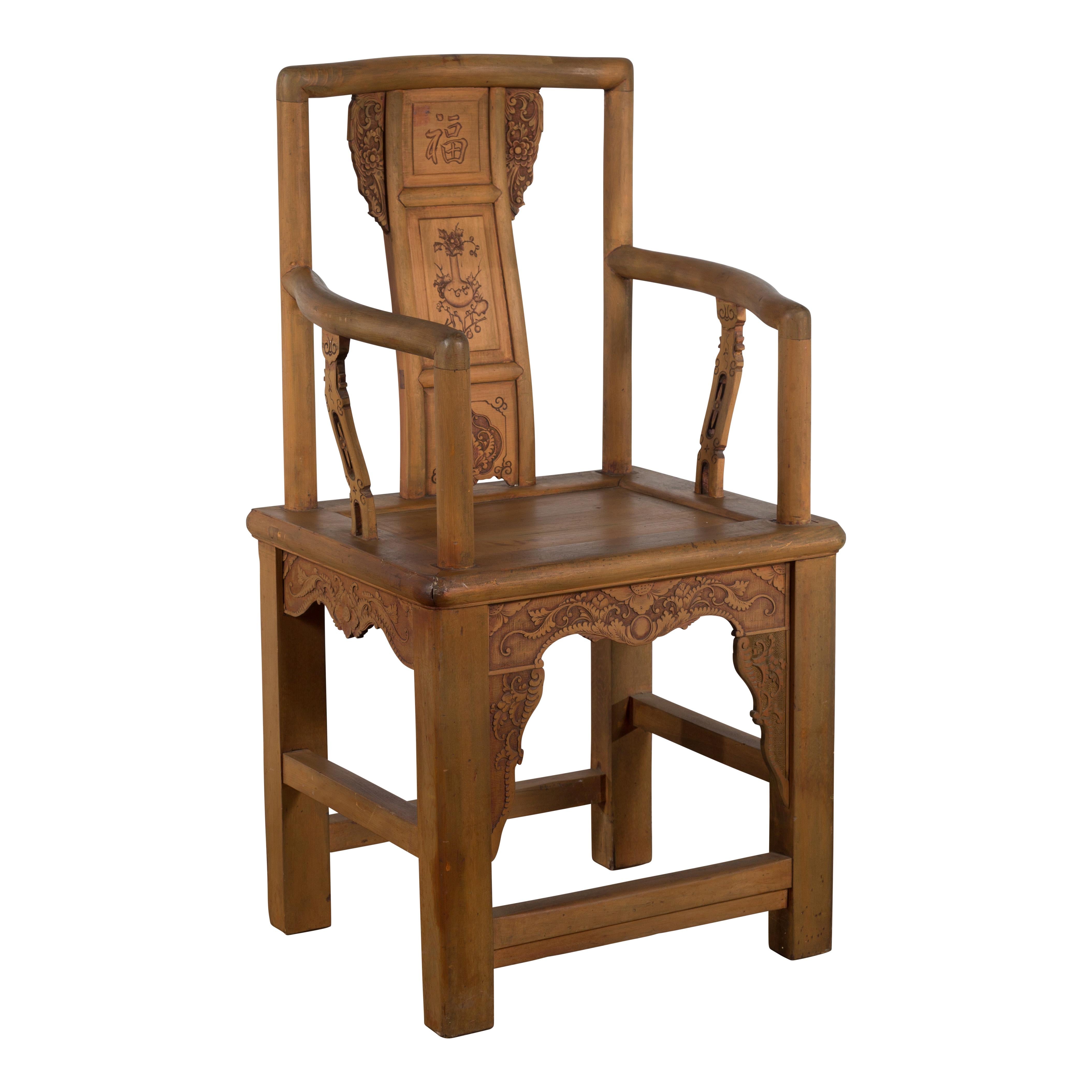 A Chinese Qing Dynasty period carved wooden lacquered elmwood armchair from the 19th century, with traditional auspicious motifs. Created in China during the Qing Dynasty, this elm armchair features a straight, slightly in-curving back showcasing a
