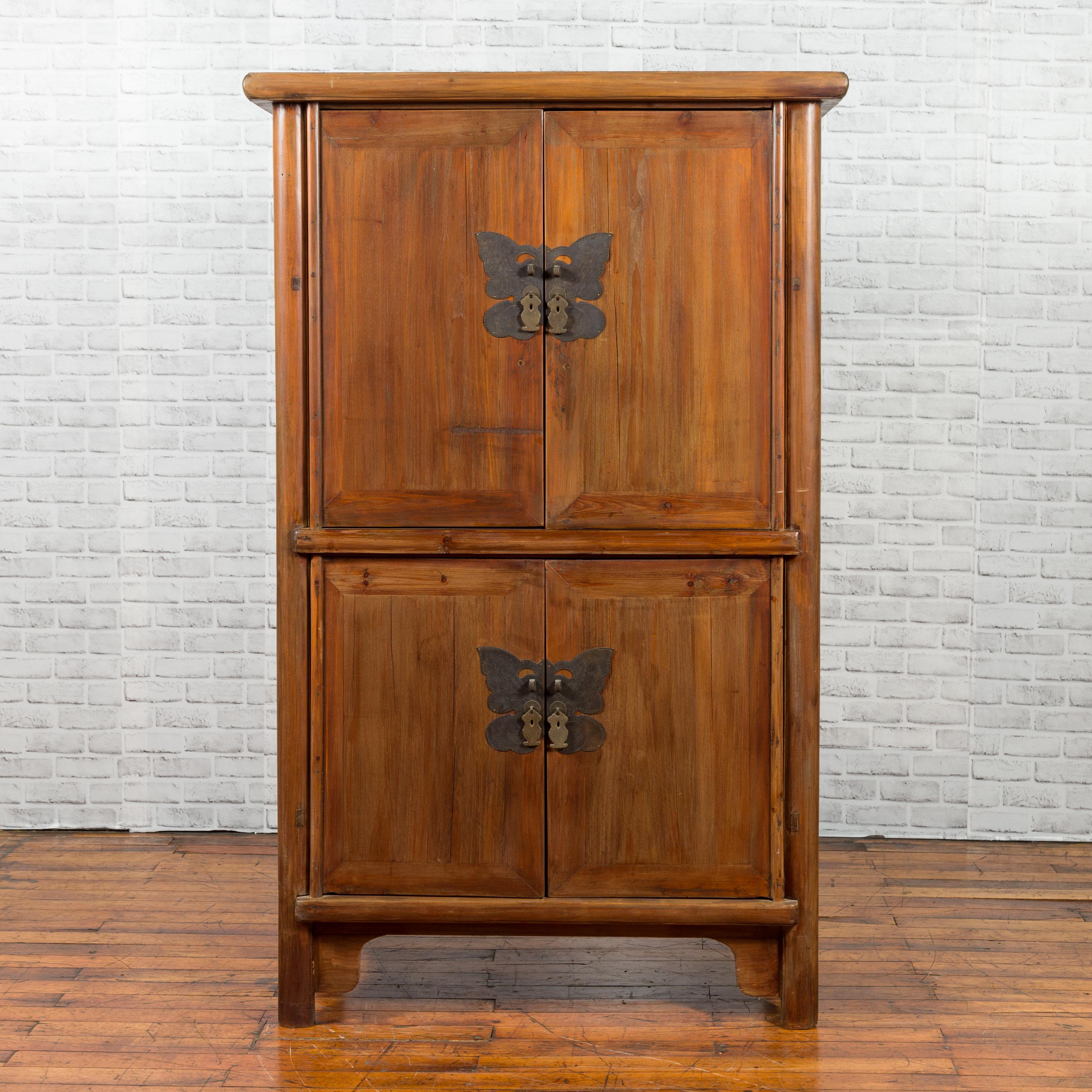 A Chinese Qing Dynasty wedding cabinet from the 19th century, with two pairs of double doors and large butterfly hardware. Created in China during the Qing Dynasty, this wedding cabinet features two pairs of double doors, each fitted with a cut-out