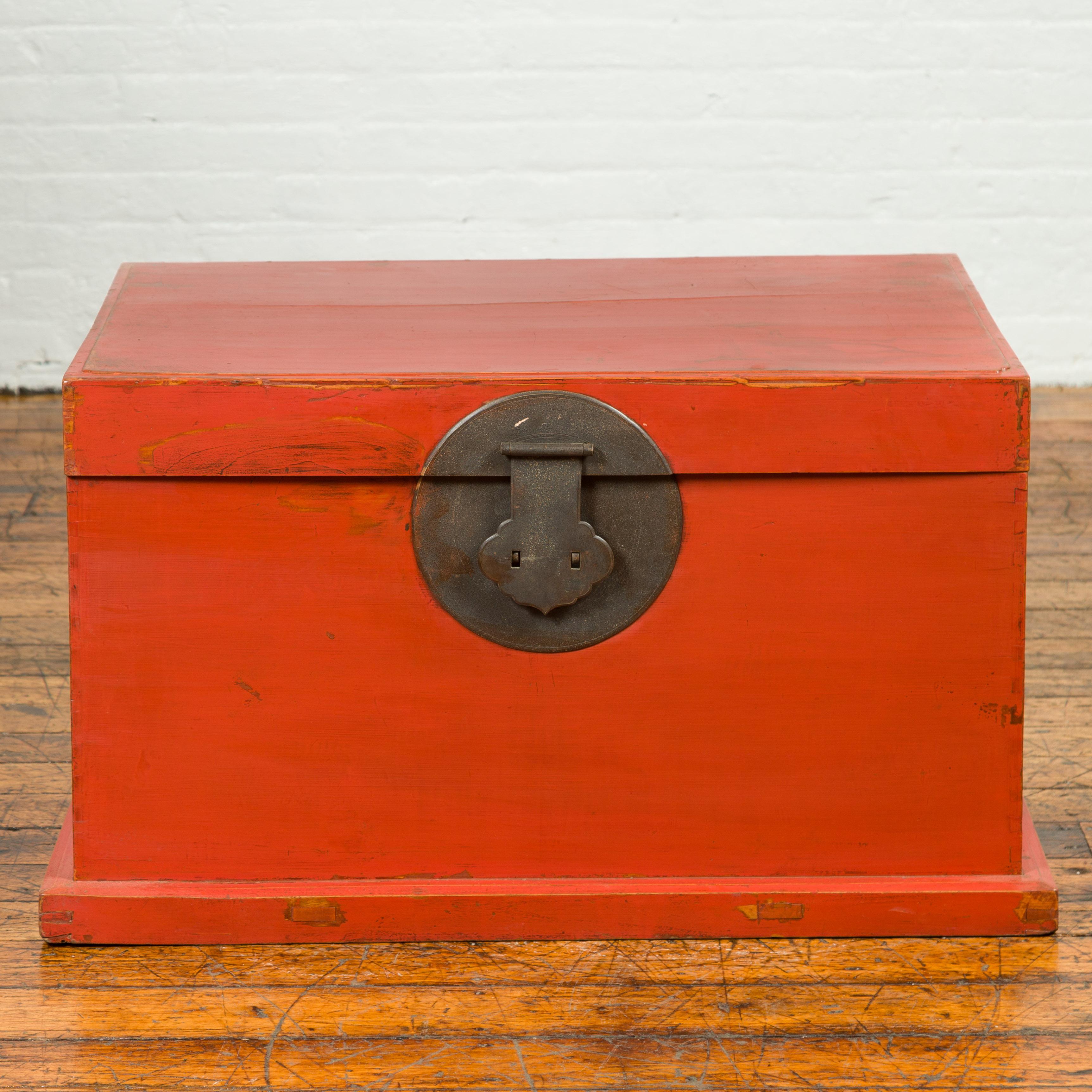 A Chinese Qing dynasty period red lacquered blanket chest from the 19th century, with iron hardware. This exquisite Chinese Qing dynasty period blanket chest, dating back to the 19th century, presents a captivating blend of functionality and