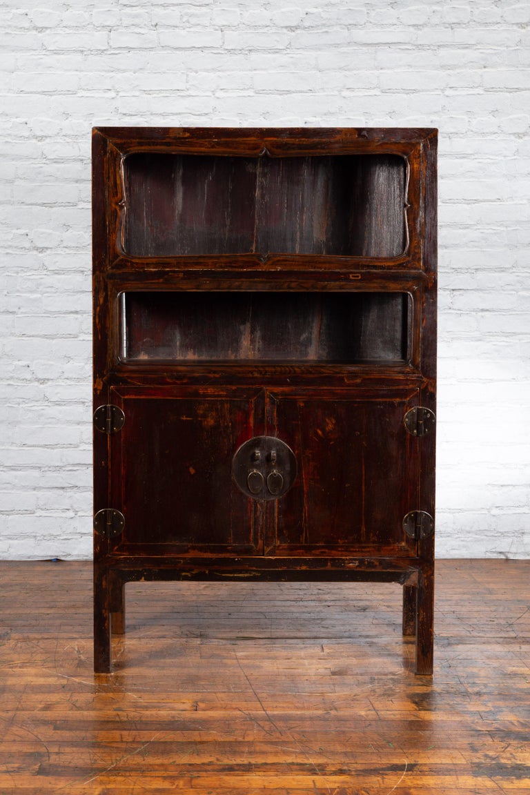 A Chinese Qing Dynasty period display cabinet from the 19th century, with dark reddish brown lacquer and brass hardware. Created in China during the Qing Dynasty, this display cabinet features a linear silhouette perfectly complimented by a dark