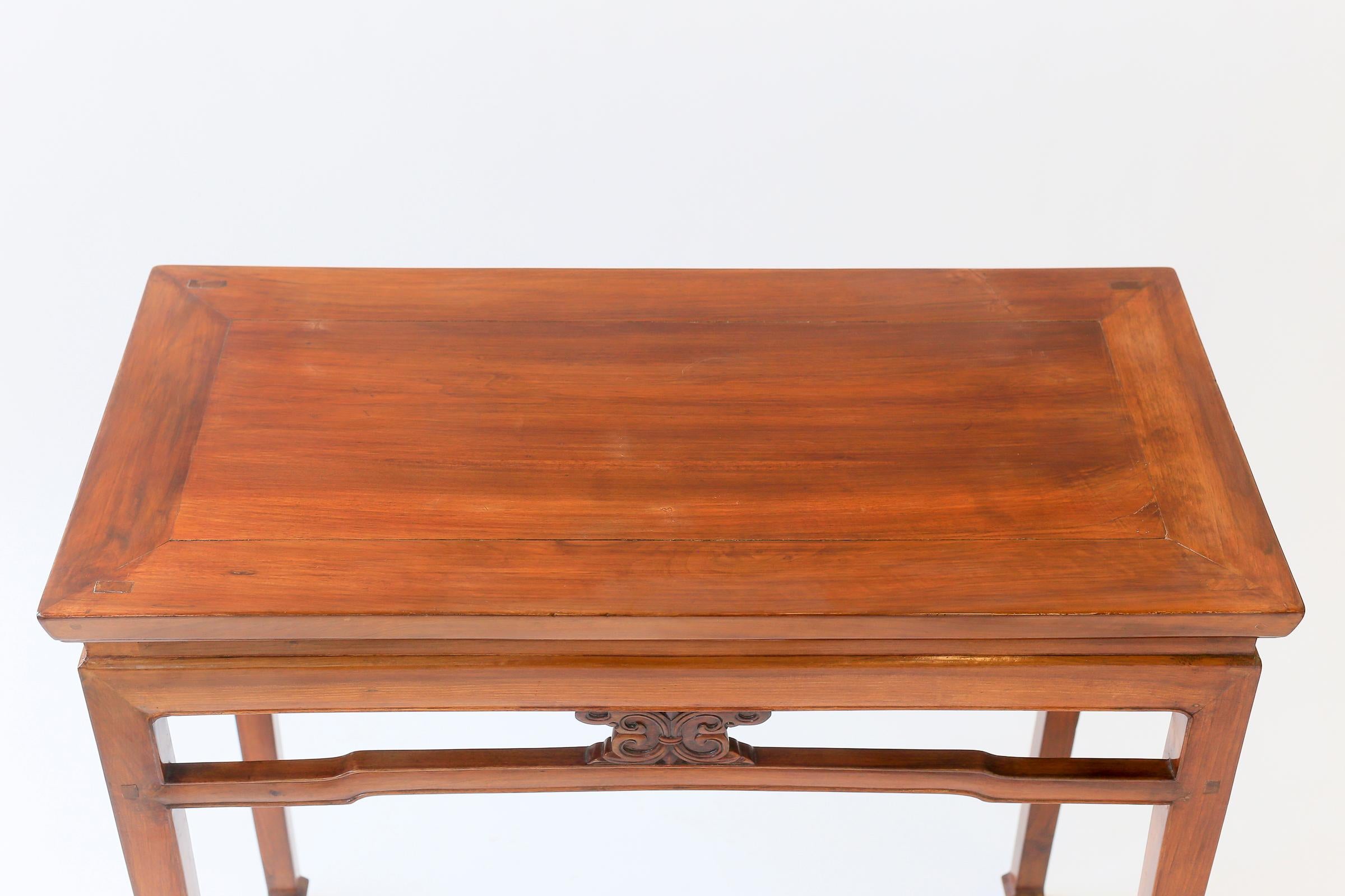 A graceful 19th century Chinese hardwood altar table, with a carved apron. The table features for decorative carved elements, one on each side, between the top and stretcher .

Tables of this style, particularly from the Ming and Qing dynasties,