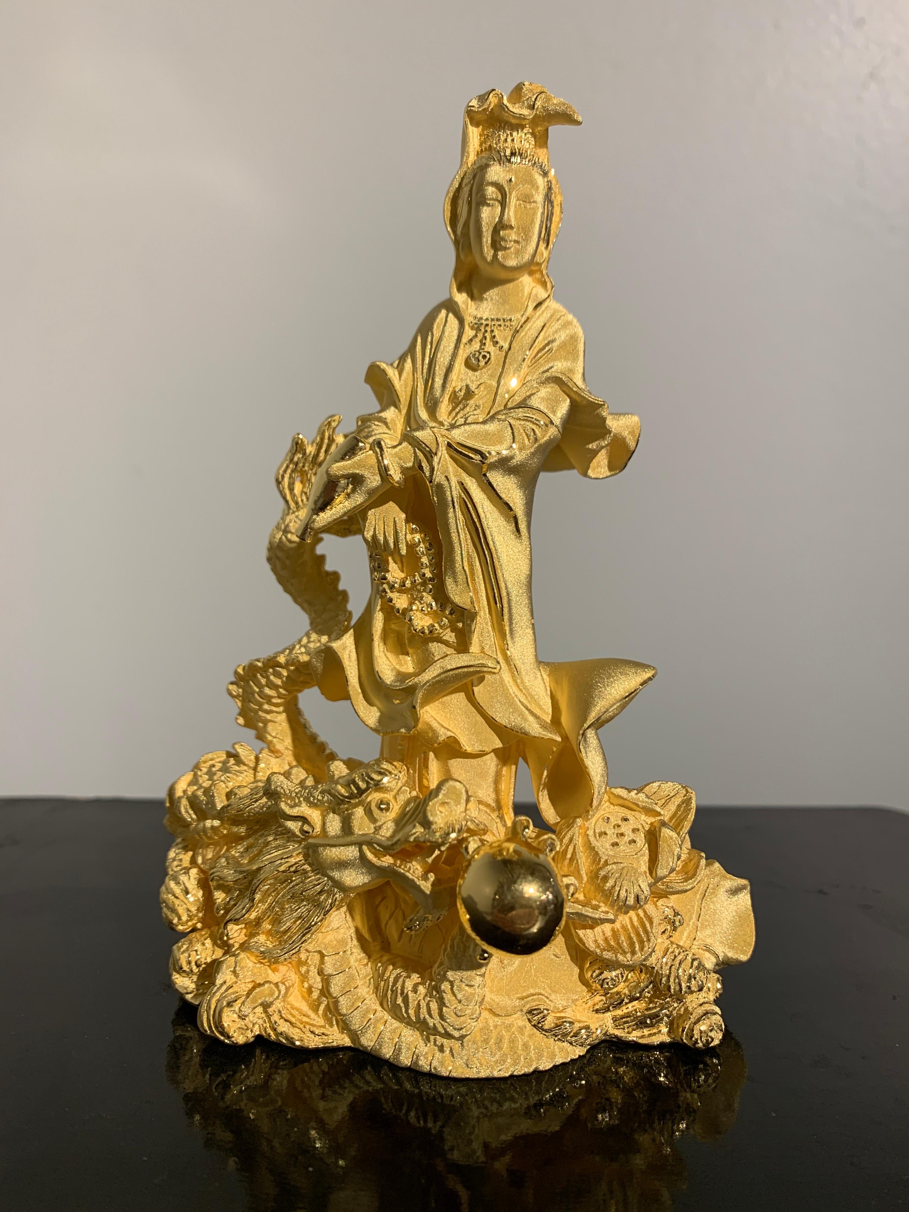 A wonderful Chinese sculpture of the Goddess of Mercy, Guanyin, riding on the back of a dragon. Crafted of 24k (marked 999.9) textured yellow gold, 56.74g. 

Guanyin, also known as Kwan Yin and Avalokiteshvara, is sculpted as a strong figure with a