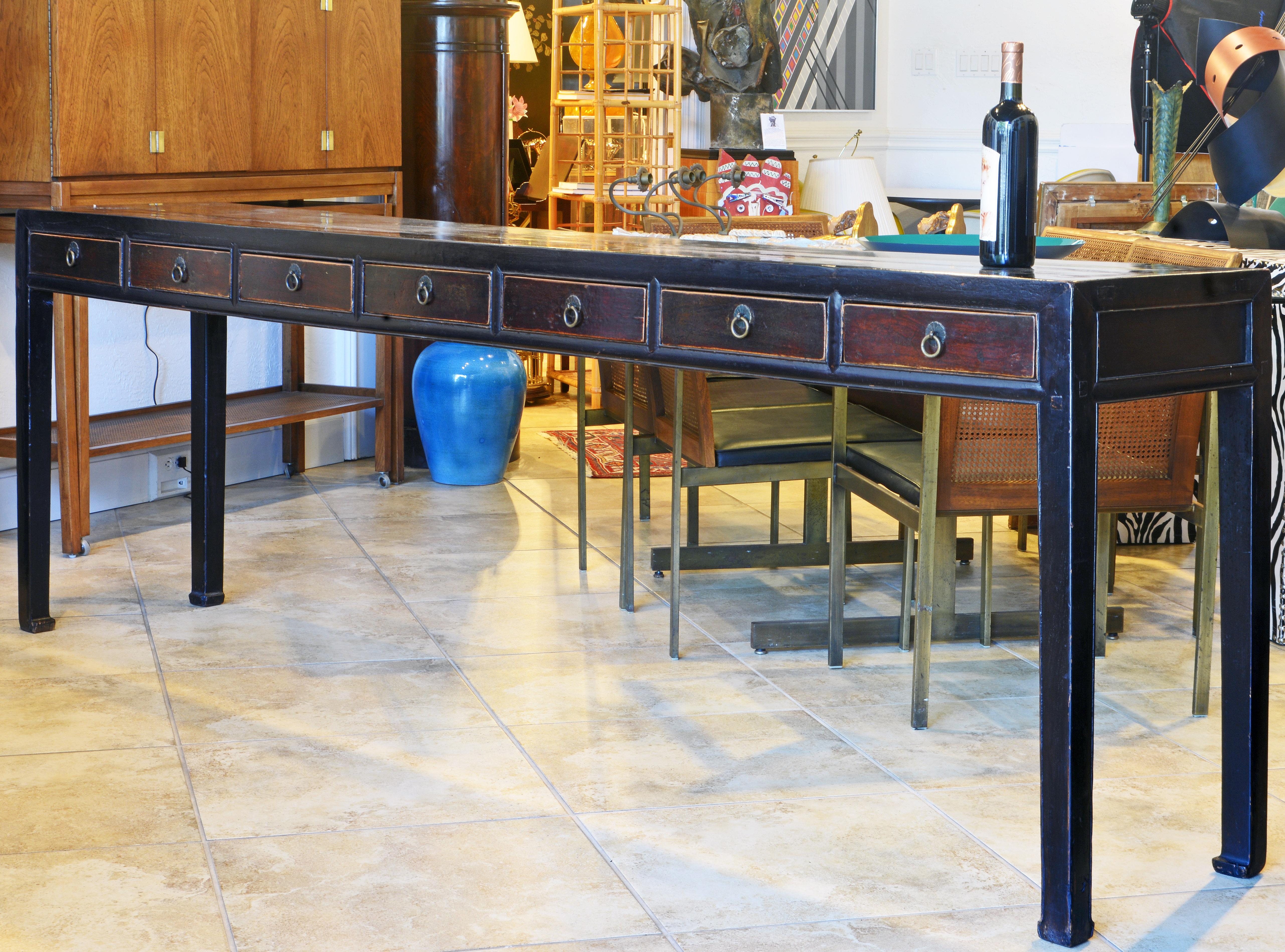 This extra long Chinese console table or altar table dates to the late 19th century and has been gracefully restored. It features a lacquered top above 7 short wood color drawers resting on square Ming style legs. The table looks good from both
