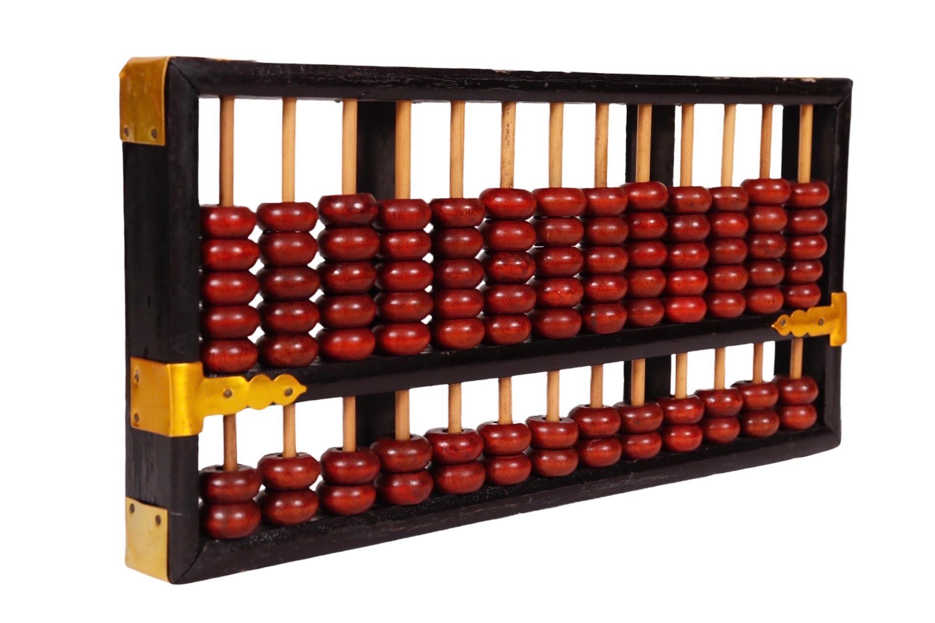 A Chinese abacus dating from 1912 to 1949. A black lacquered frame secured with brass corners houses 13 bamboo rods, each with five and two red wooden beads. The original label underneath reads 