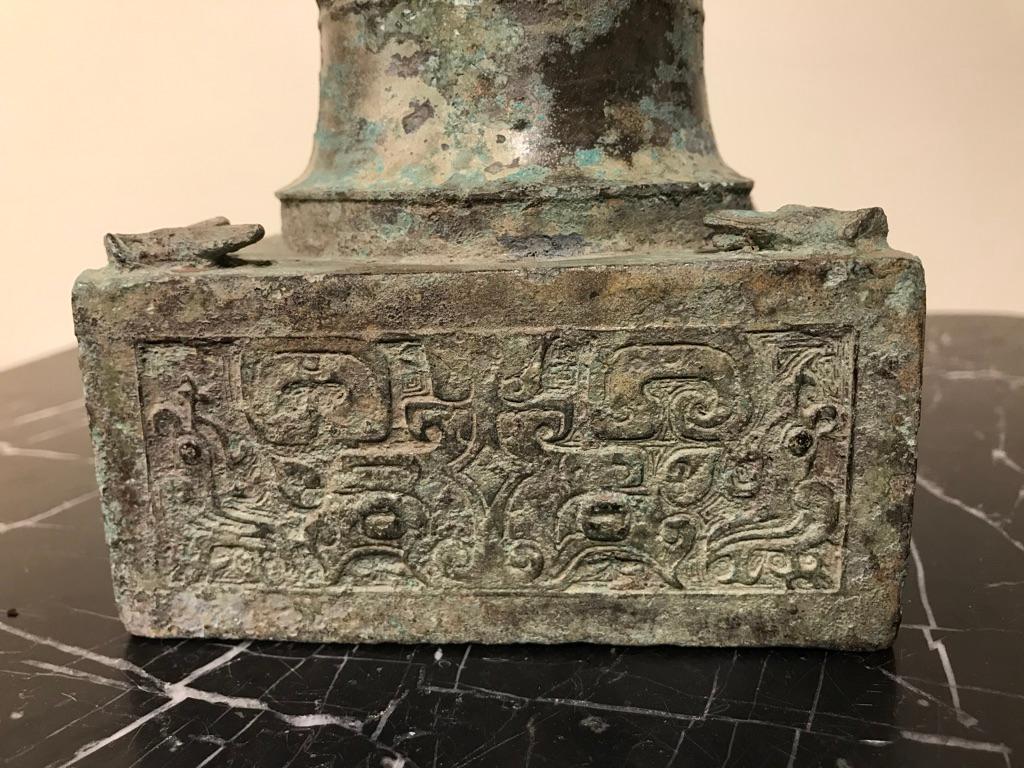 A vase-form Chinese bronze vessel with integral square plinth. Incised with exquisite Archaistic designs on the plinth and the waist of the vase. Wonderful oxidized gray-green verdigris surface. The unusual base with bronze flies on each of the four