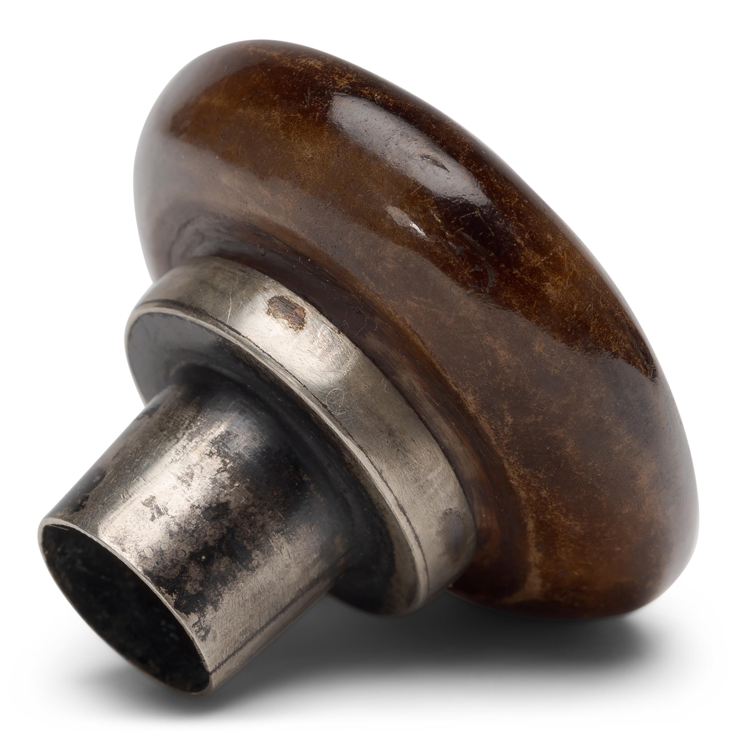 This unusual object is an early 20th century opium pipe bowl, carved of agate and fitted with a brass collar. Minimally decorated, the stone of this pipe bowl was likely selected for its resemblance to tortoiseshell. Unlike a tobacco pipe, the opium