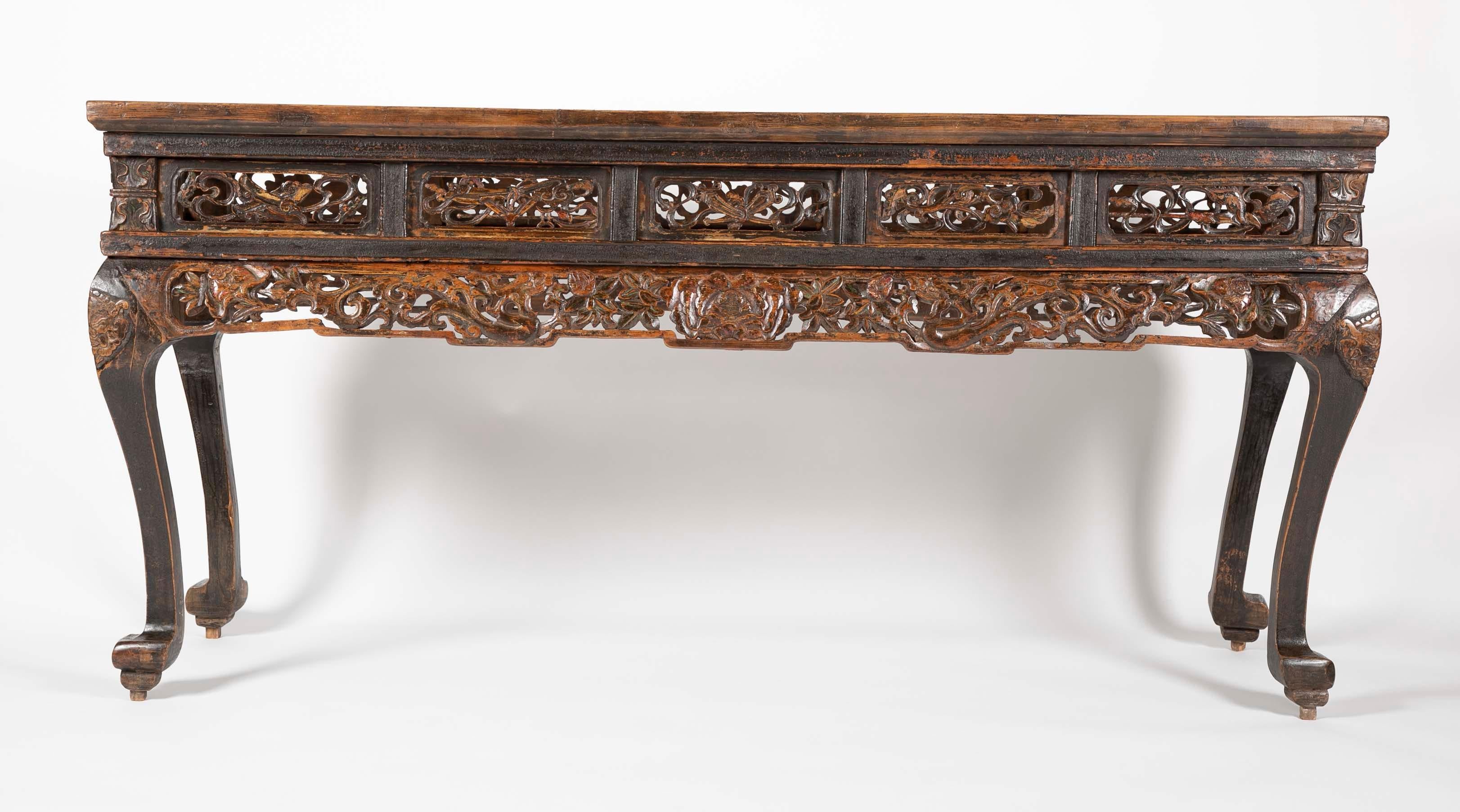 A handsome 19th century Chinese altar table with traces of the original paint. The apron decorated with open-work carvings of a central lotus flower flanked by dragons and pomegranates. The knees of the elegant cabriole legs carved with masks of