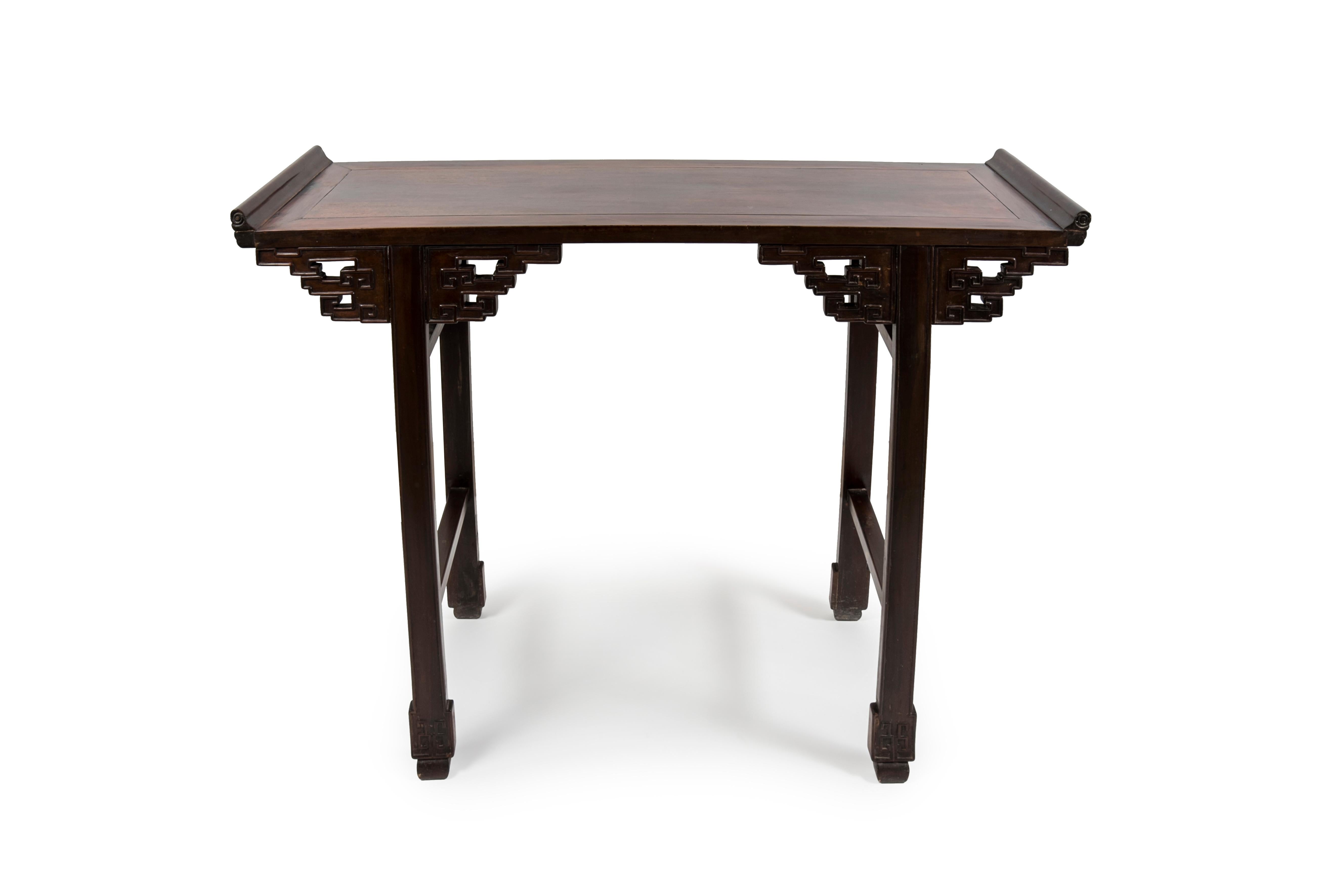 Altar chino utilizado también como consola o mesa auxiliar. De madera dura exótica, probablemente zitán, con una pátina oscura. Presenta voluptuosos bordes abocinados y enjutas talladas con motivos de nubes. La consola se alza sobre cuatro pies
