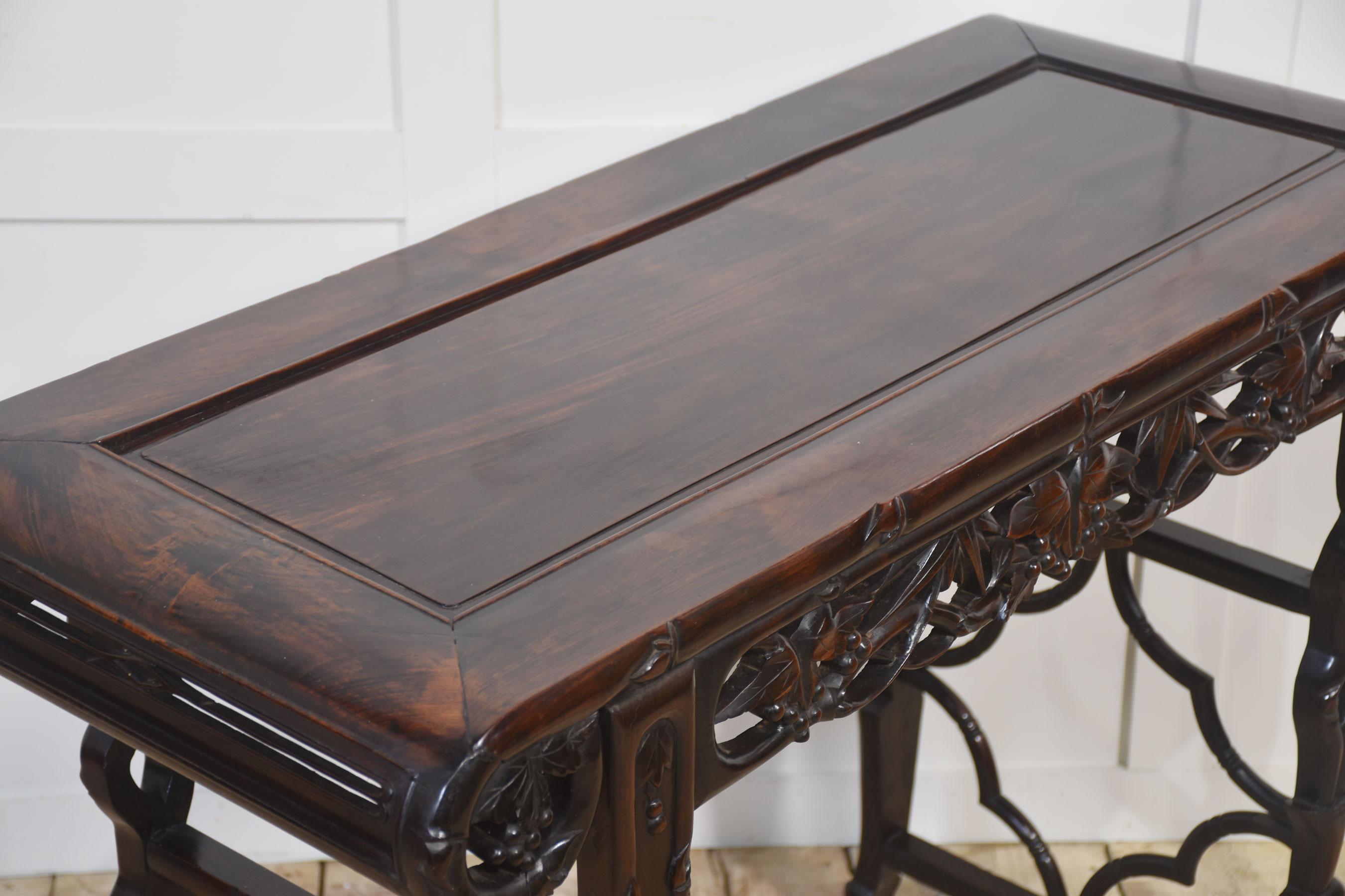 Magnifique table d'autel chinoise ancienne, finement fabriquée en bois dur riche avec une finition profonde et polie. Le plateau rectangulaire repose sur un tablier finement sculpté de motifs de feuillage et de baies entrelacés, symbolisant la
