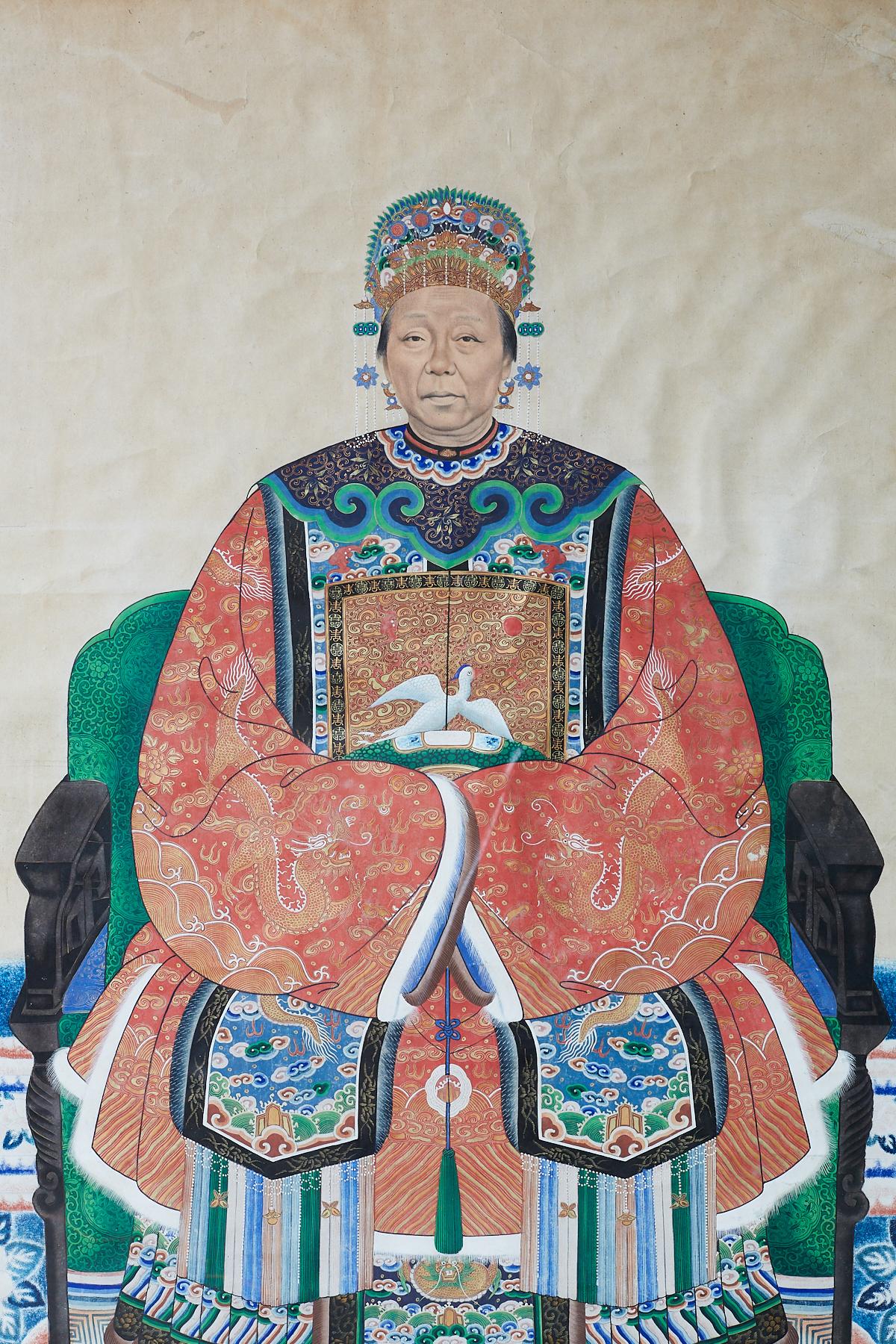 Large 19th century Qing dynasty ancestral matriarch scroll portrait painting. Features a matriarch in semi-formal ceremonial court attire decorated in vibrant colors. Depicted sitting on a carved chair wearing a robe with cranes, dragons, and